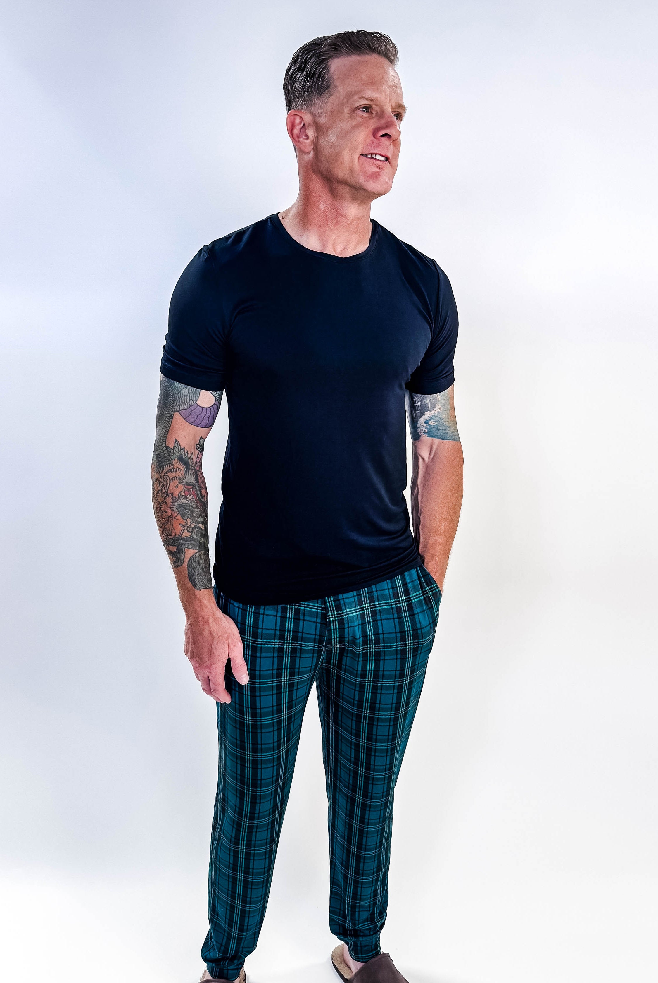 Man wearing Midnight Plaid Unisex Bamboo Joggers and a black shirt, showcasing comfort and style.