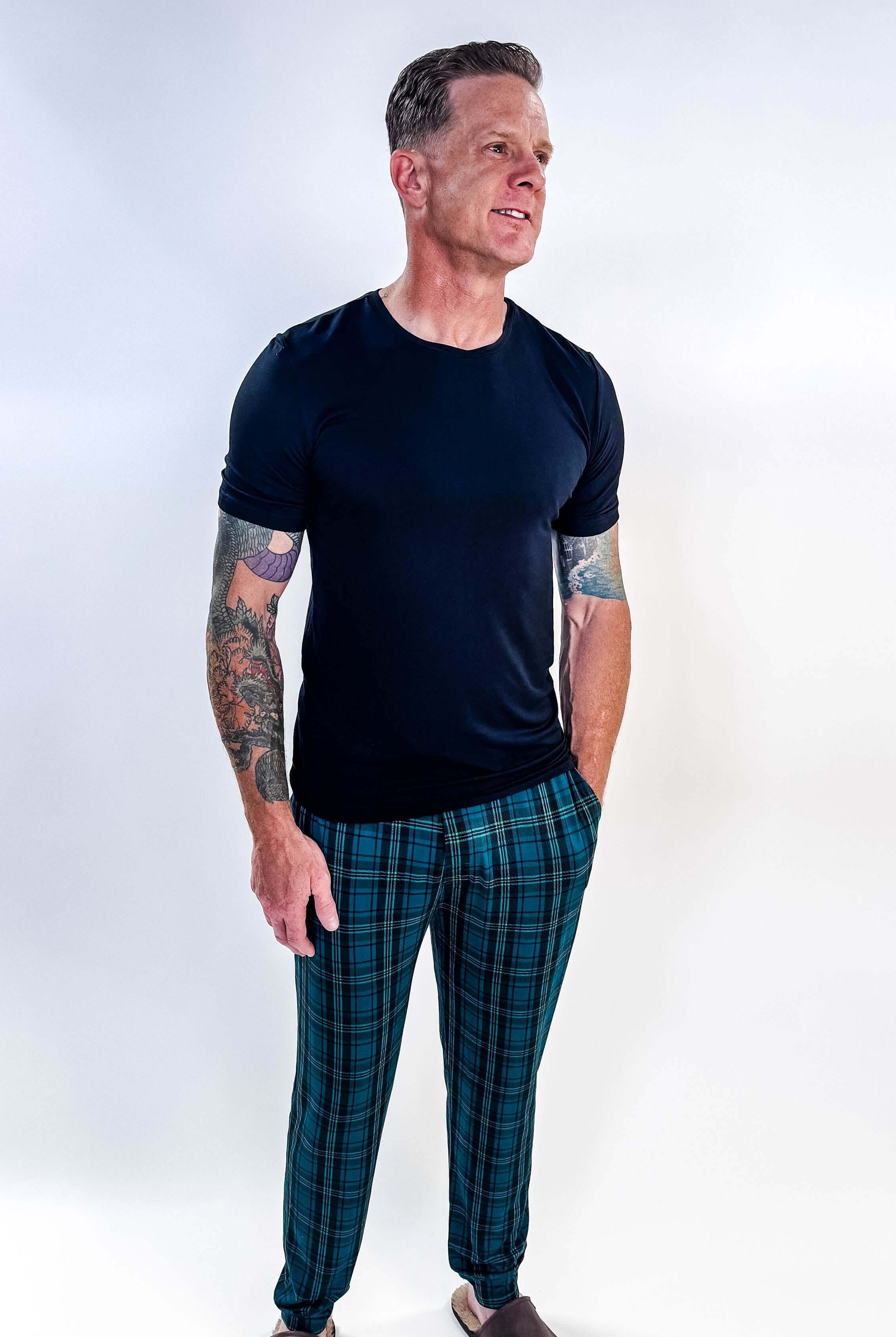 Man wearing Midnight Plaid Unisex Bamboo Joggers and a black shirt, showcasing comfort and style.