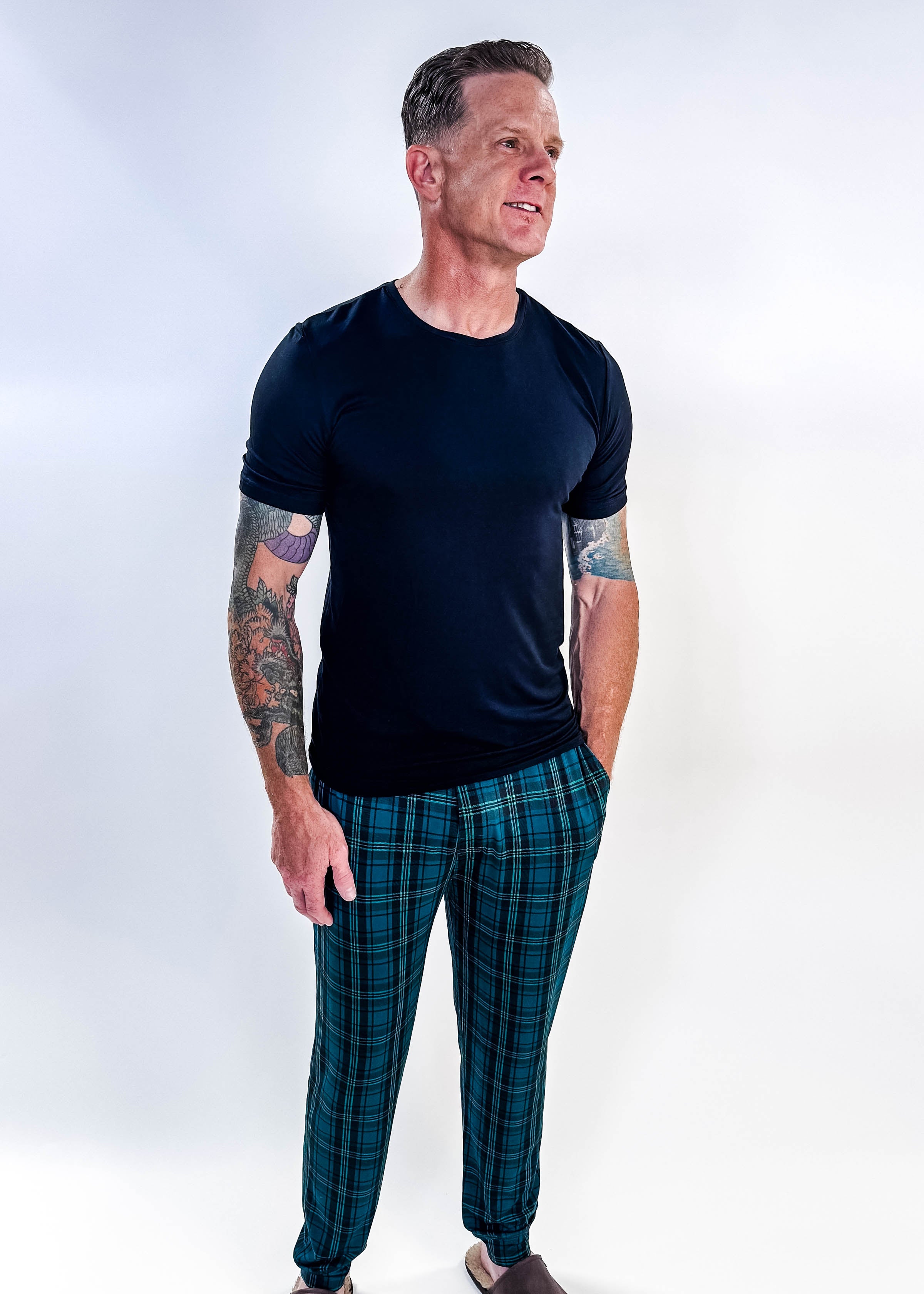 Man wearing Midnight Plaid Unisex Bamboo Joggers and a black shirt, showcasing comfort and style.