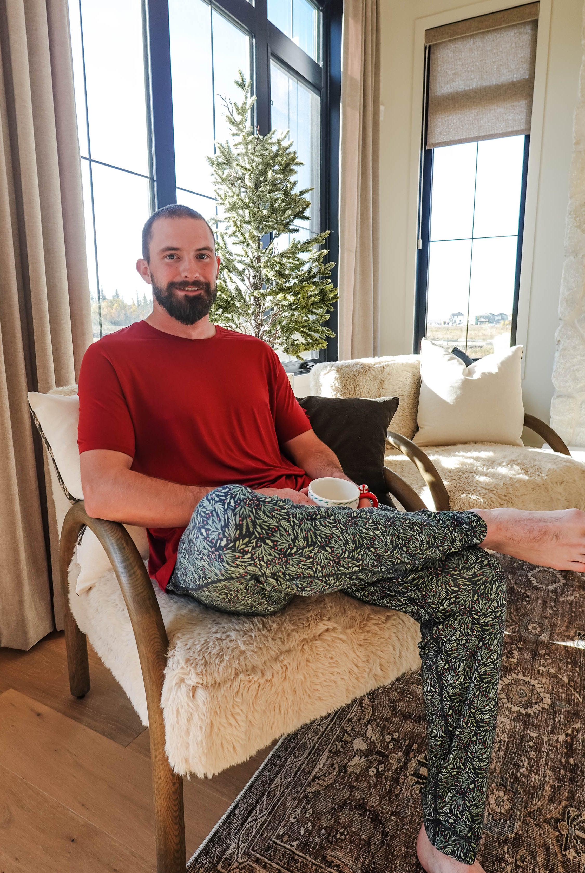 Man sitting comfortably in Mistletoe Print Unisex Bamboo Jogger, enjoying a drink in a cozy living room.