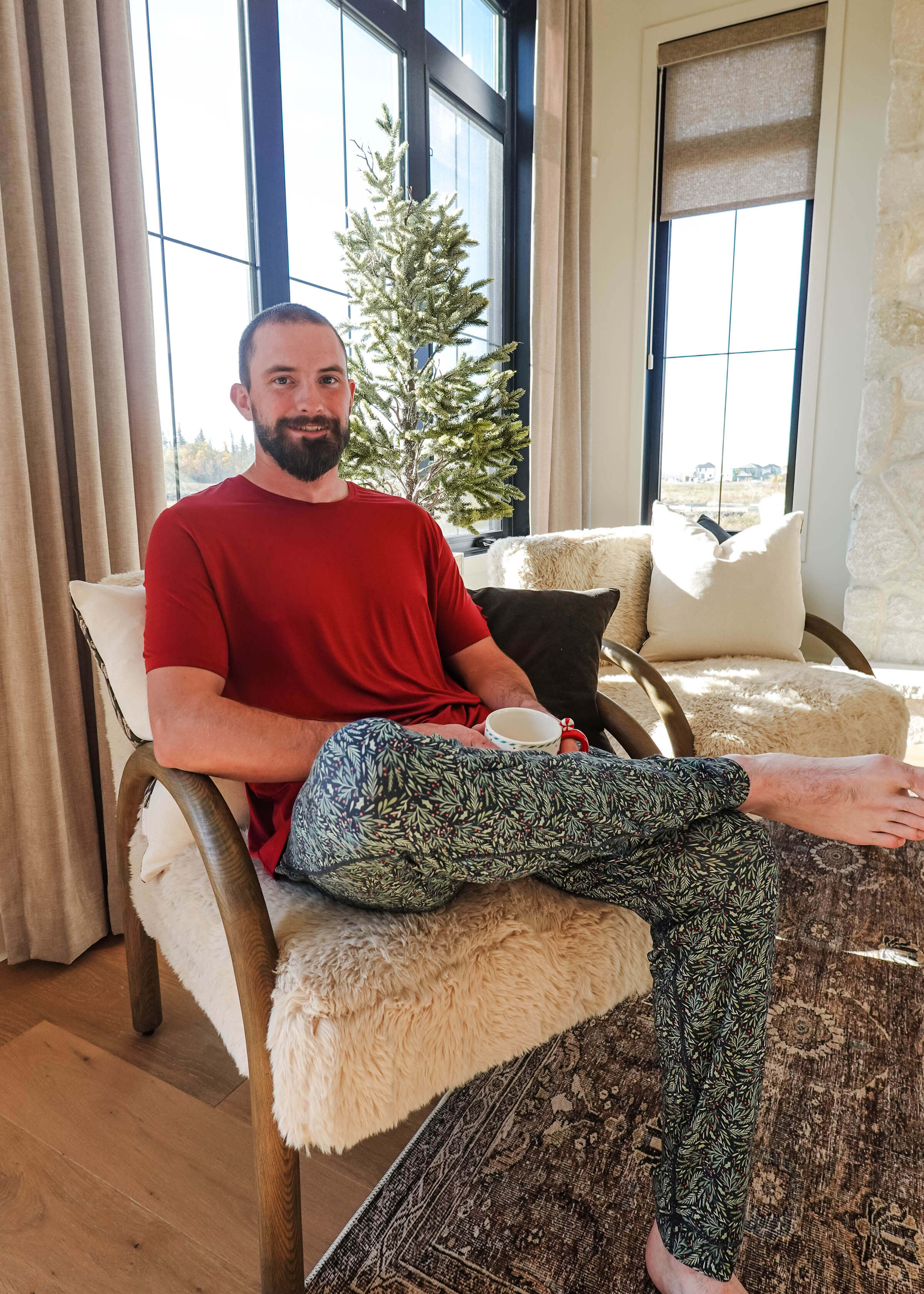 Man sitting comfortably in Mistletoe Print Unisex Bamboo Jogger, enjoying a drink in a cozy living room.