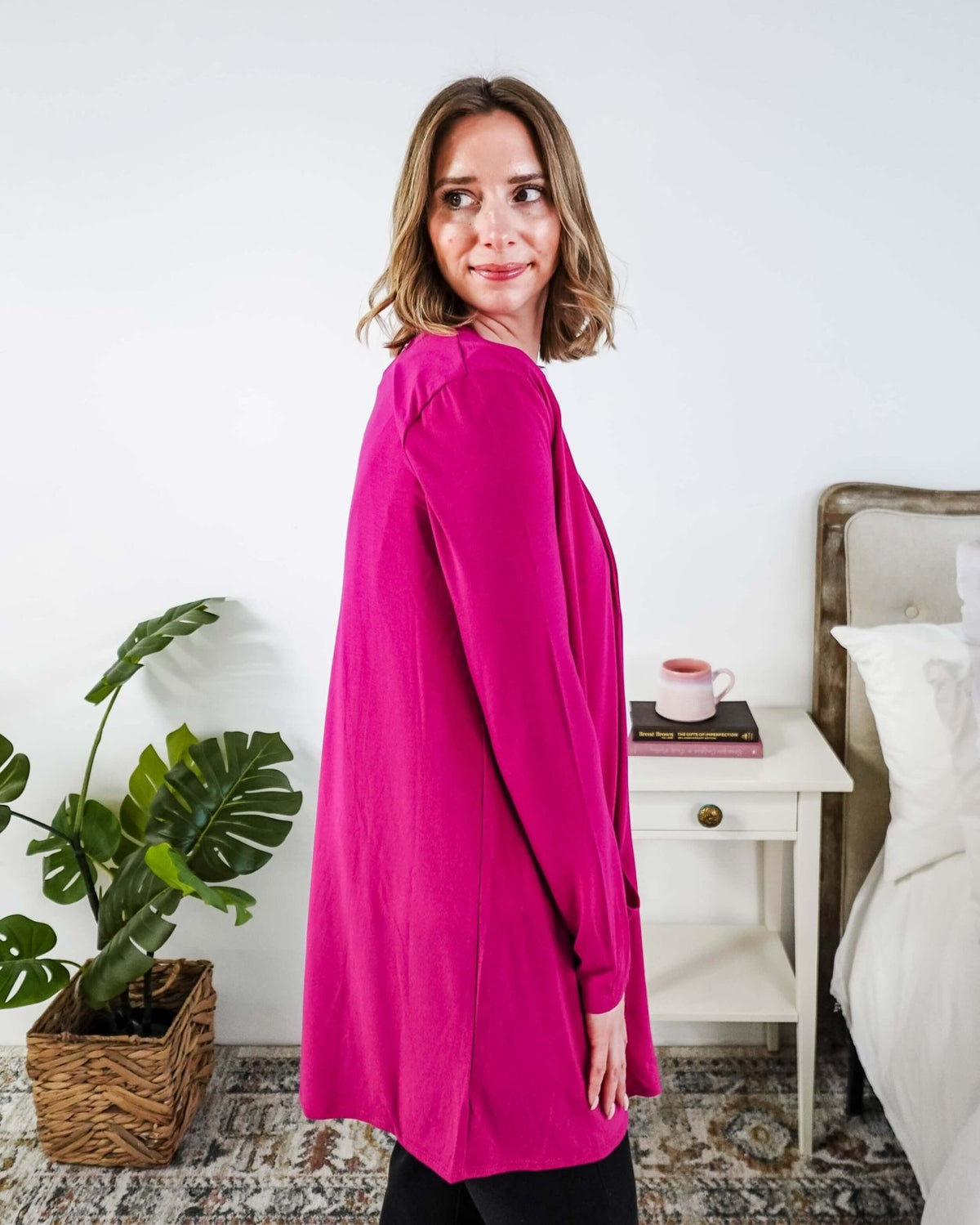 Woman in a bright pink cardigan standing in a bedroom. Scarlett Ellie Summer Open Lightweight Cardigan | Cloud Nine Pajamas