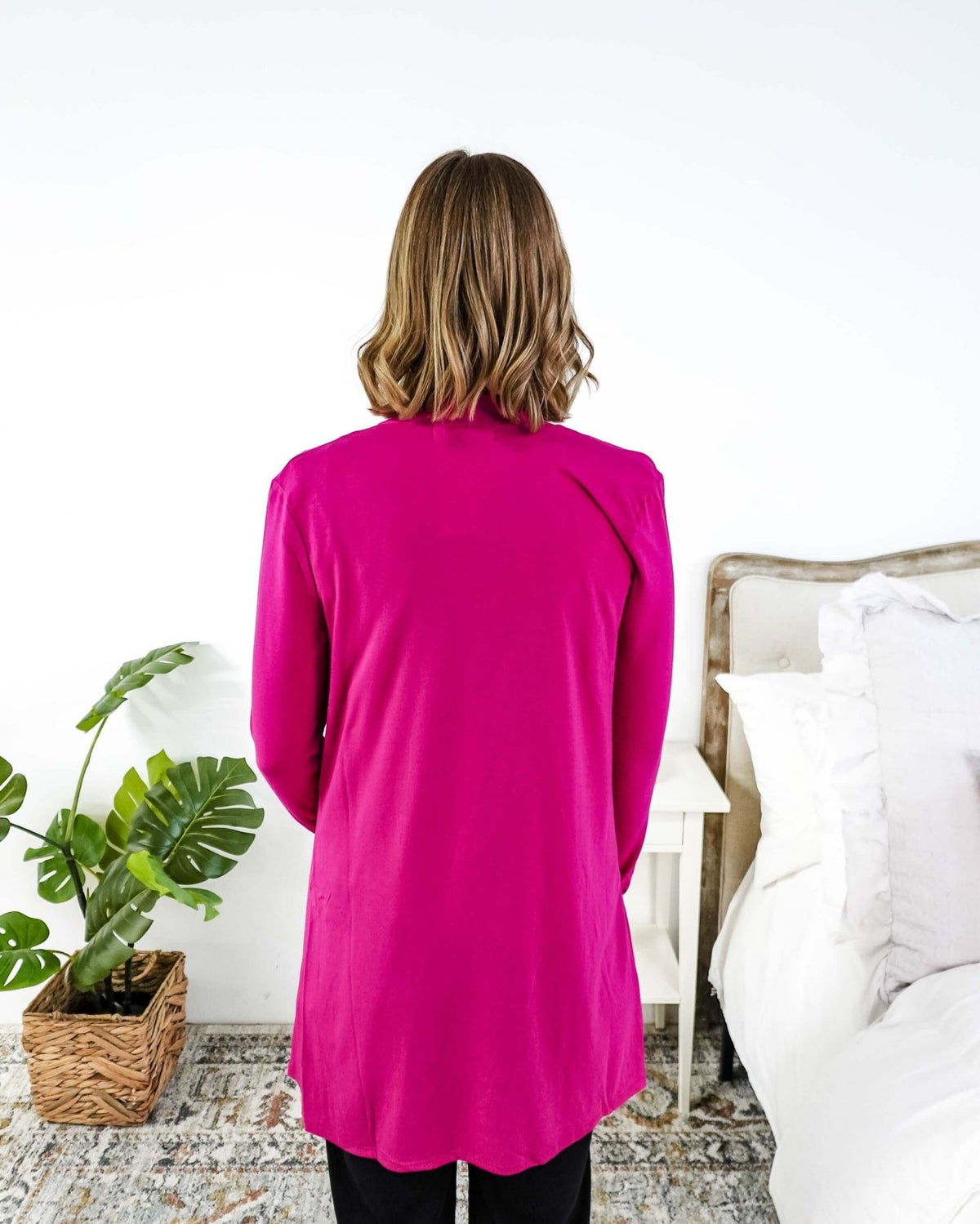 Women wearing a bright pink long-sleeve cardigan in a bedroom setting. Scarlett Ellie Summer Open Lightweight Cardigan | Cloud Nine Pajamas
