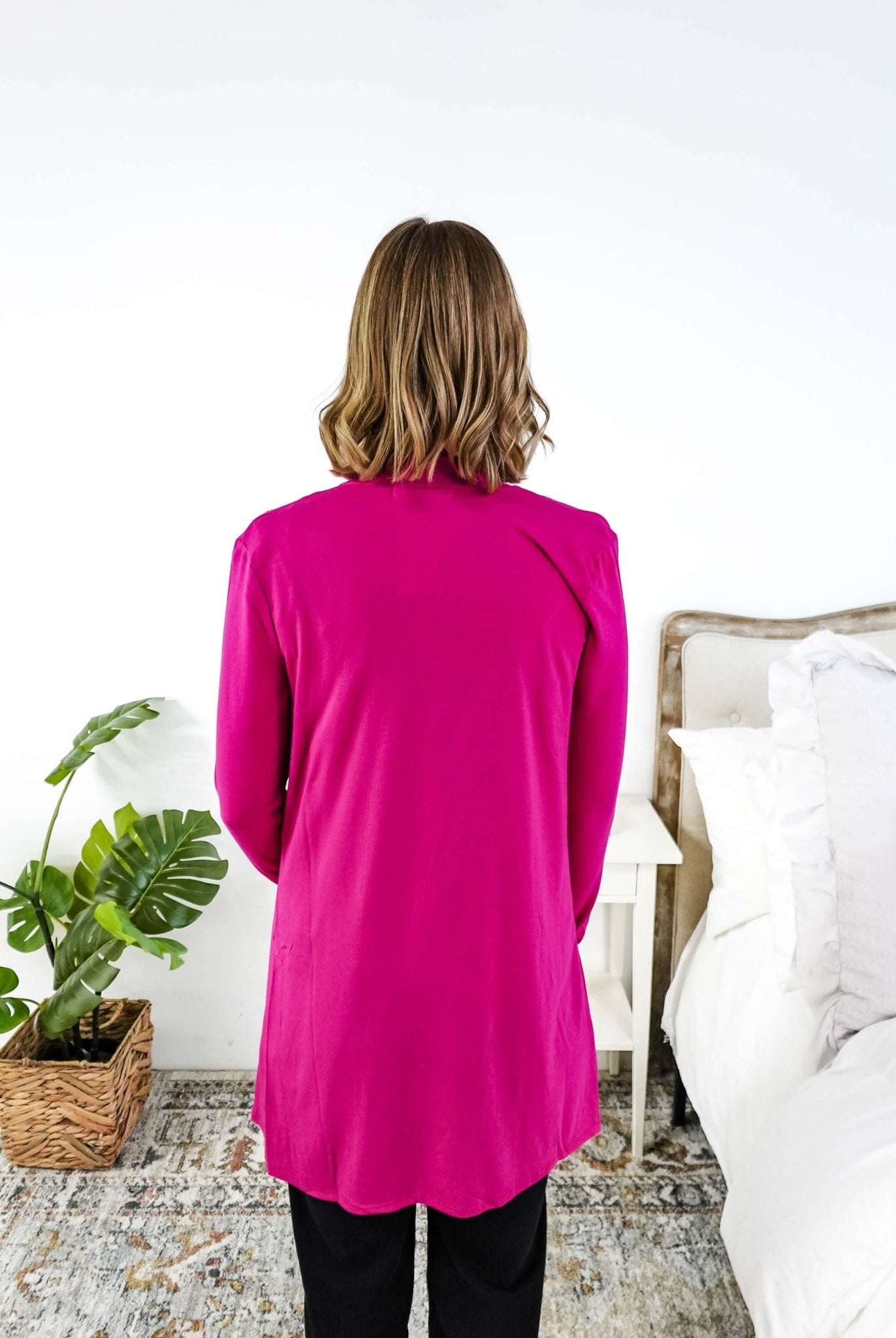 Women wearing a bright pink long-sleeve cardigan in a bedroom setting. Scarlett Ellie Summer Open Lightweight Cardigan | Cloud Nine Pajamas