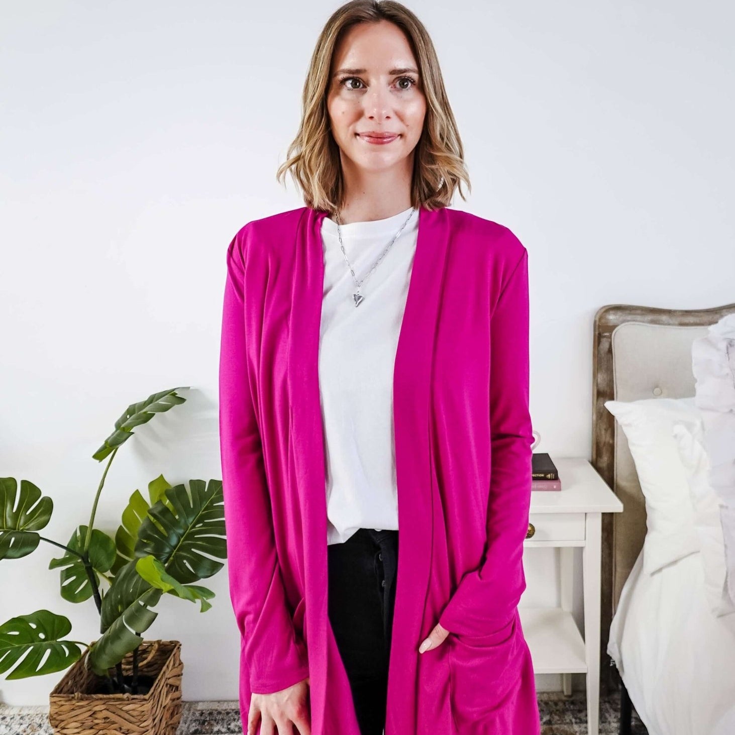 Woman wearing a bright pink cardigan in a bedroom setting Scarlett Ellie Summer Open Lightweight Cardigan | Cloud Nine Pajamas