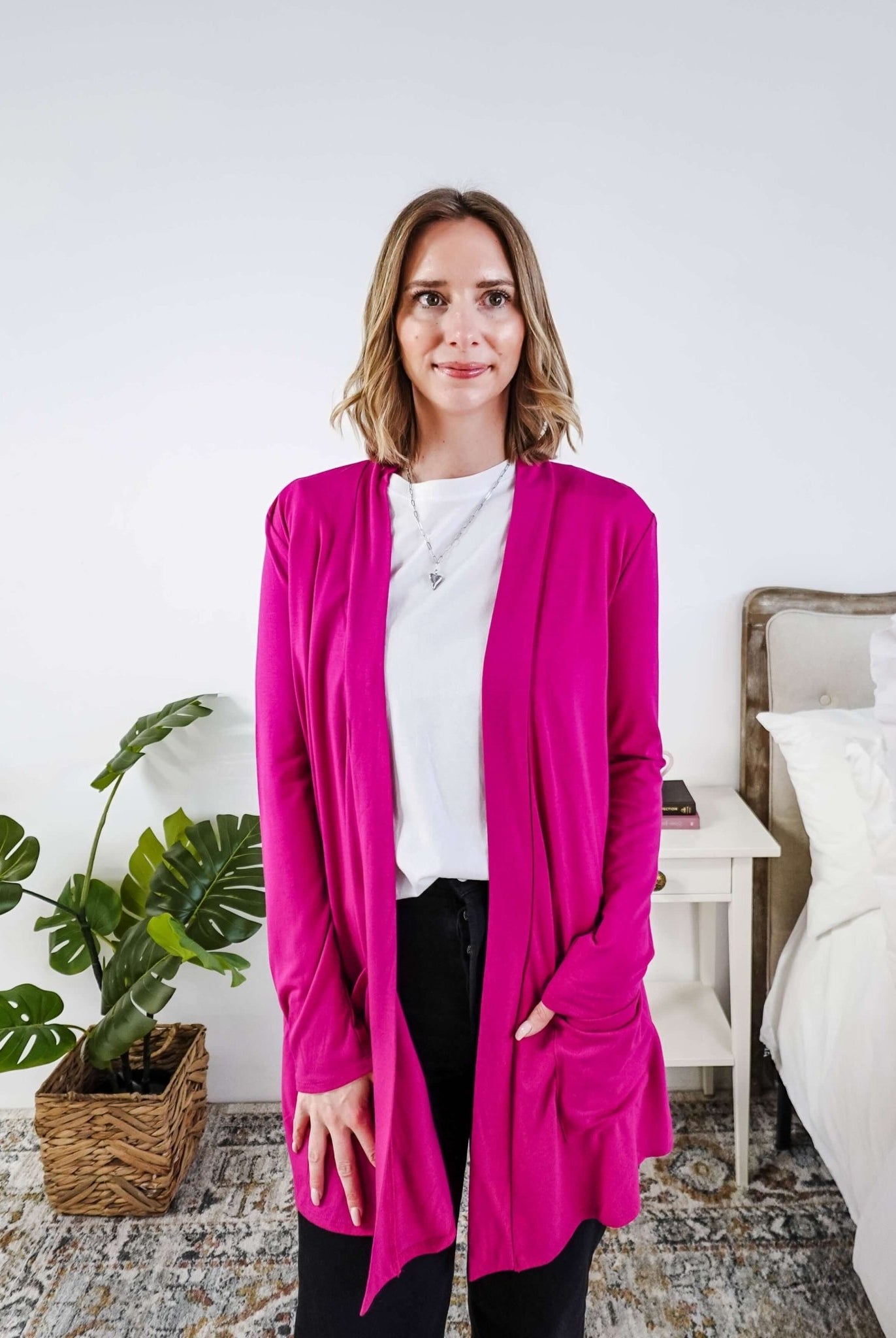 Woman wearing a bright pink cardigan in a bedroom setting Scarlett Ellie Summer Open Lightweight Cardigan | Cloud Nine Pajamas
