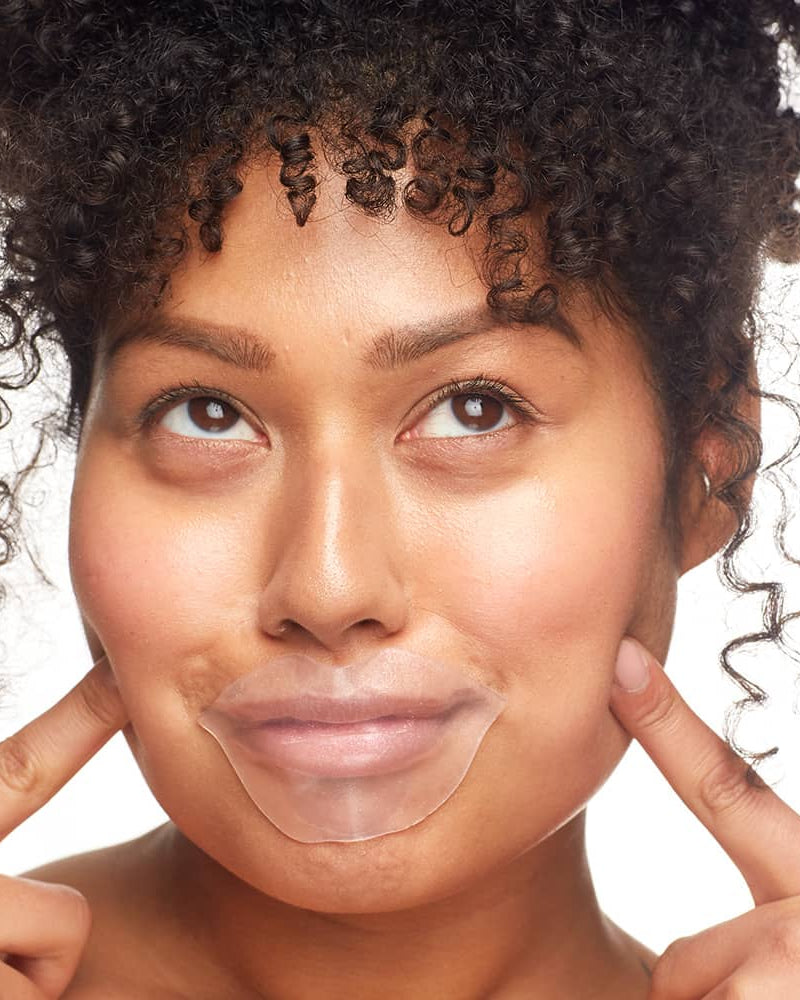 Woman applying Patchology FlashPatch Hydrating Lip Gels for a plump, moisturized pout.
