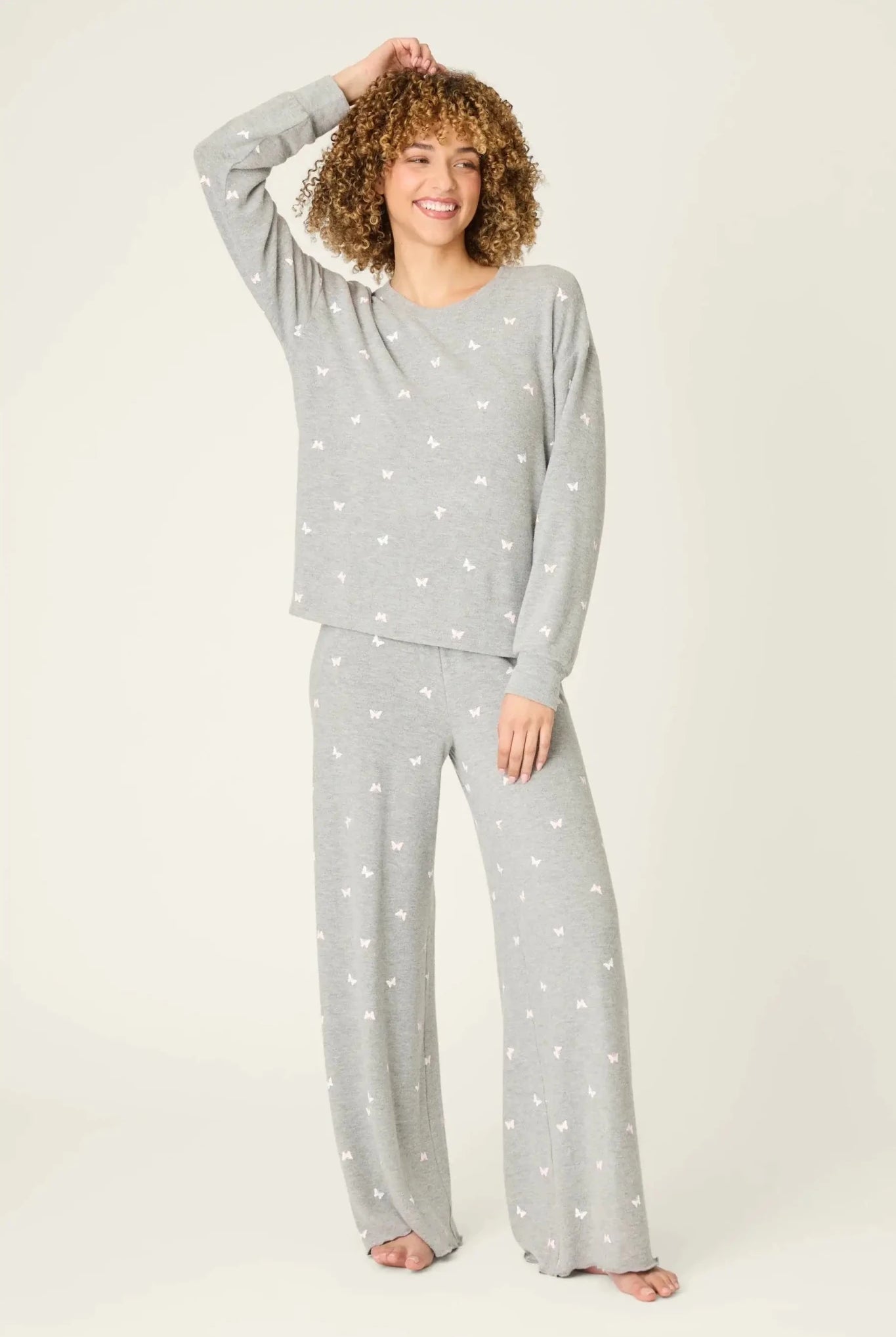 Woman wearing the PJ Salvage Peachy Butterfly Kisses Lounge Set featuring a cozy top and wide-leg pants in heathered grey.