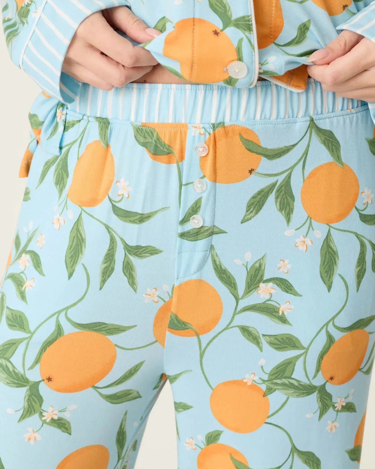 Model wearing PJ Salvage Citrus Dreams 3-Piece PJ Set featuring orange design with matching eye mask. close up of pant waist