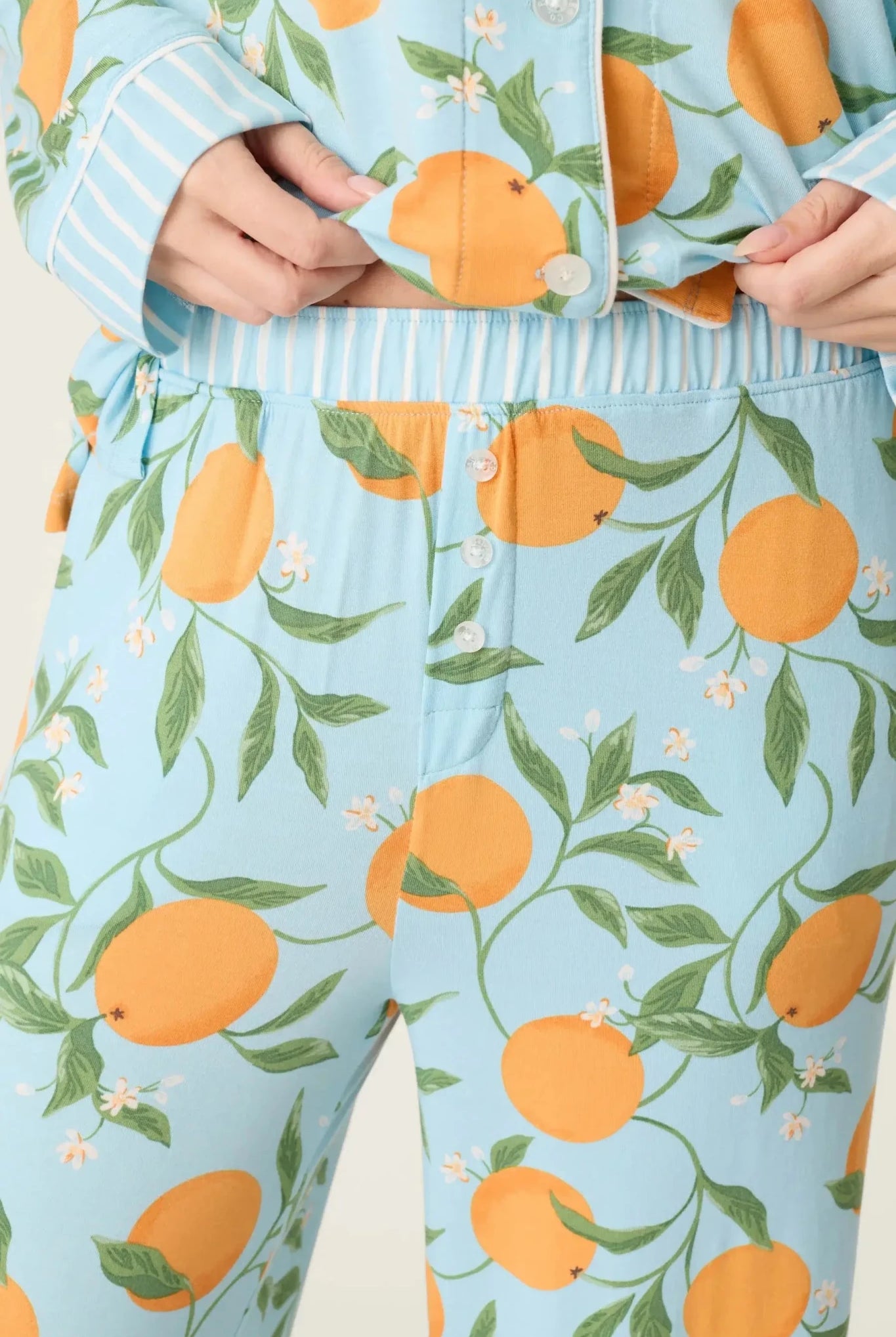 Model wearing PJ Salvage Citrus Dreams 3-Piece PJ Set featuring orange design with matching eye mask. close up of pant waist