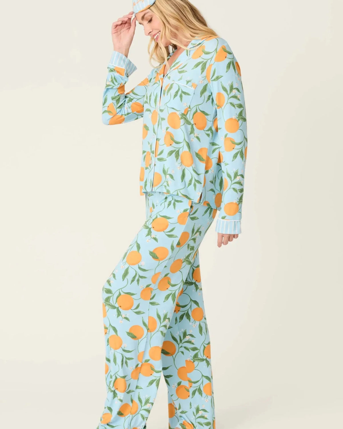 Model wearing PJ Salvage Citrus Dreams 3-Piece PJ Set featuring orange design with matching eye mask. Side View
