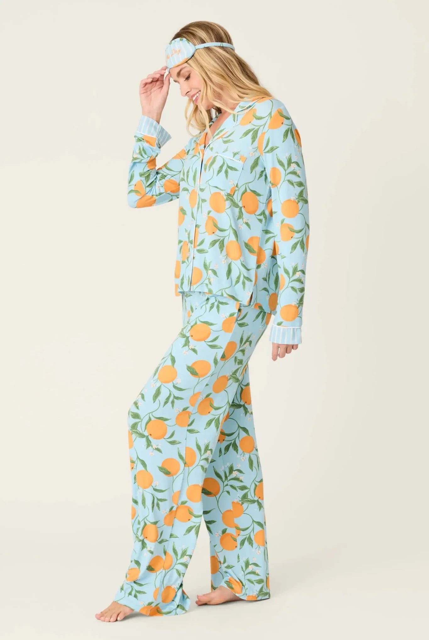 Model wearing PJ Salvage Citrus Dreams 3-Piece PJ Set featuring orange design with matching eye mask. Side View