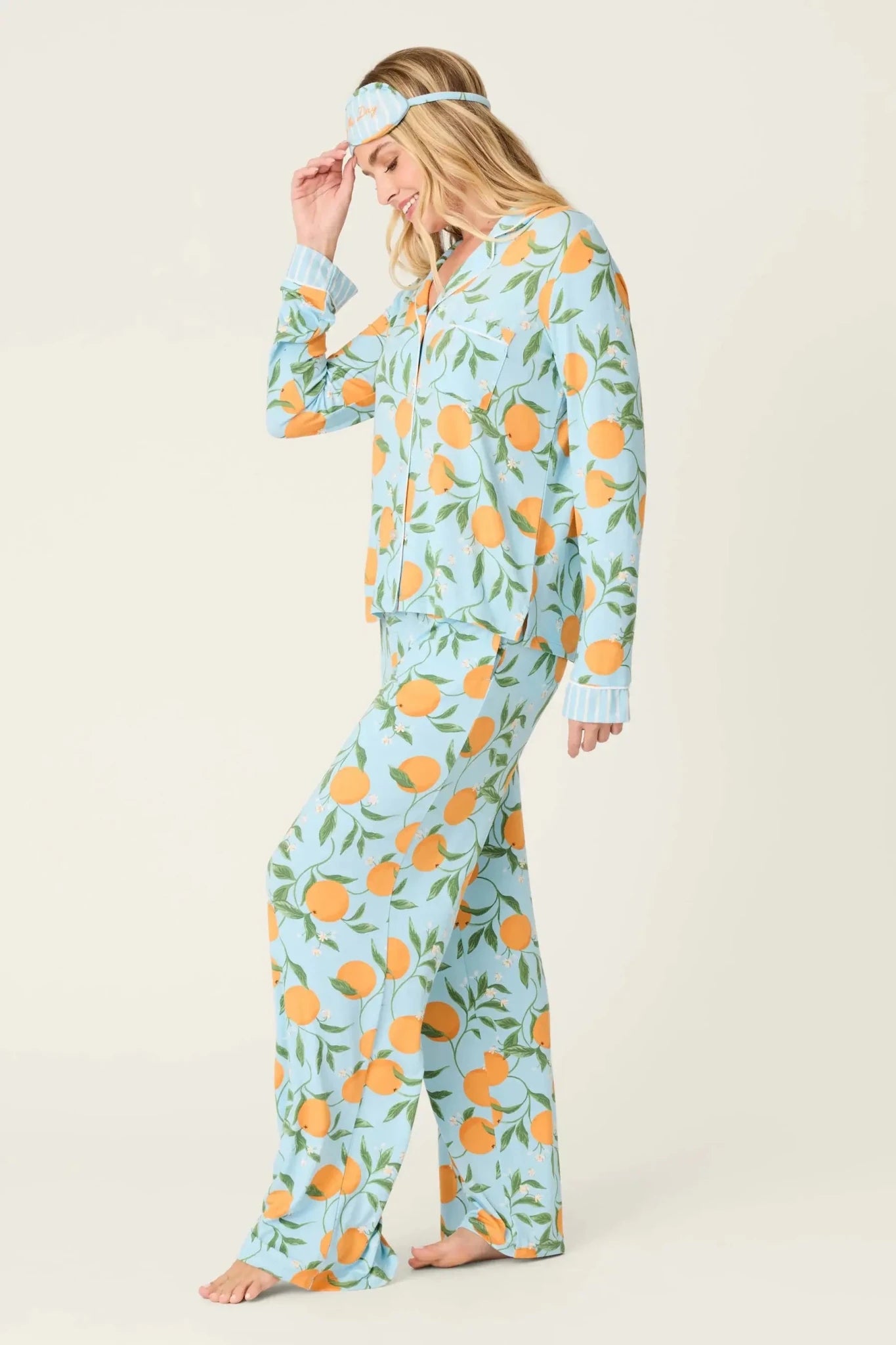 Model wearing PJ Salvage Citrus Dreams 3-Piece PJ Set featuring orange design with matching eye mask. Side View