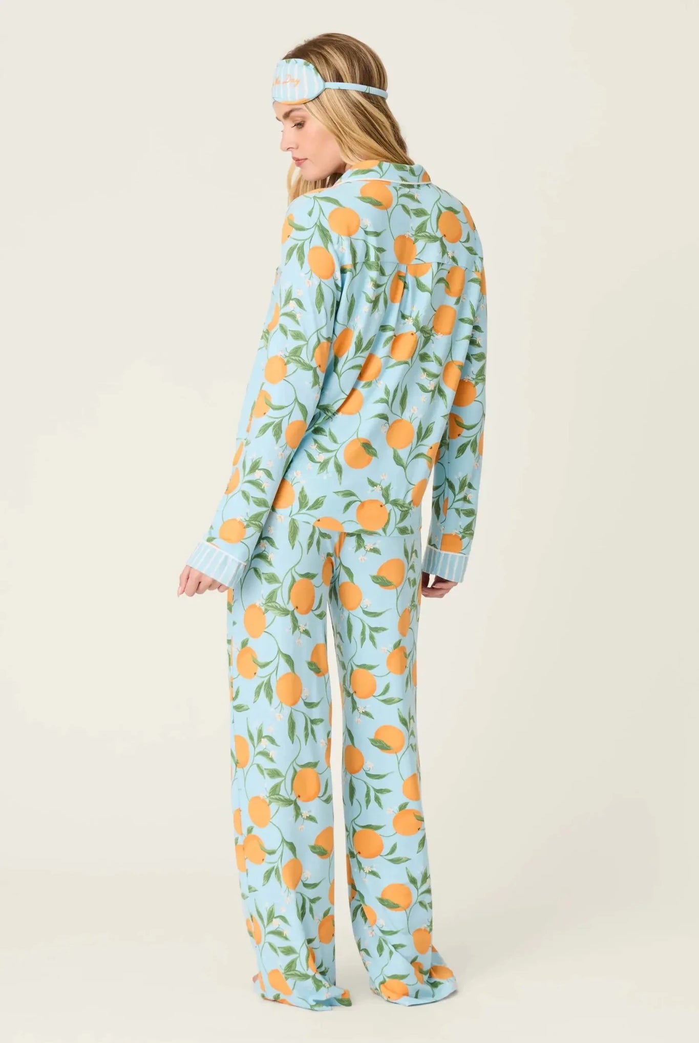 Model wearing PJ Salvage Citrus Dreams 3-Piece PJ Set featuring orange design with matching eye mask. Back View