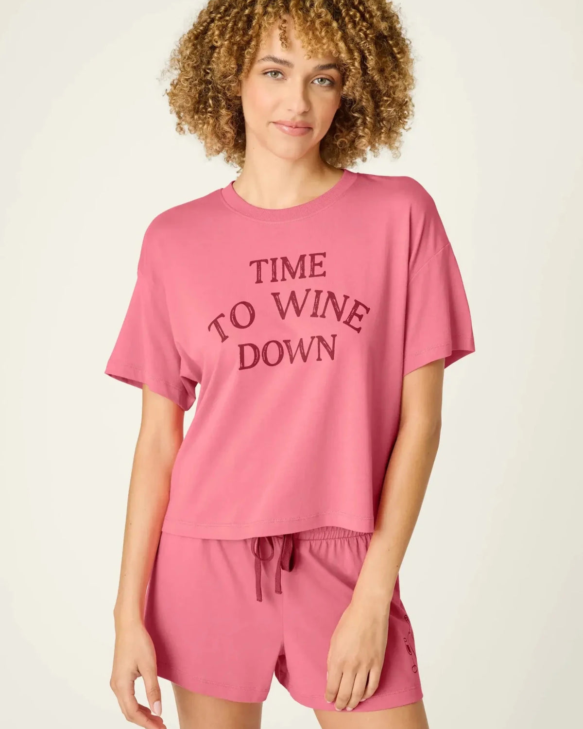 PJ SALVAGE Graphic Print Softee Tee & Short Lounge Set in "Time to Wine Down" rose pink. Model stands against a light background in a close-up shot