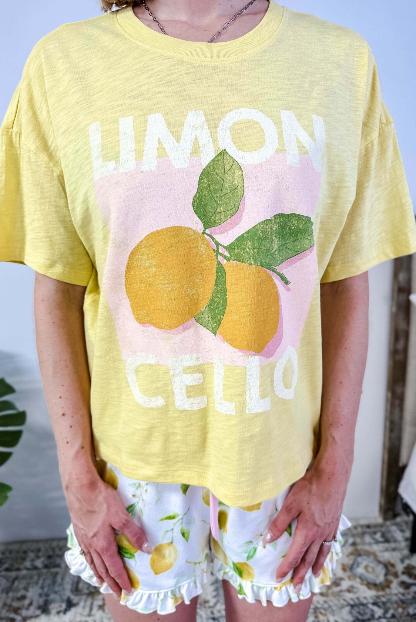 PJ SALVAGE — La Dolce Spritz Limoncello Graphic Tee & Lemon Zest Short Set shown on model in bedroom setting, close up shot of the Limoncello graphic print Tee shirt
