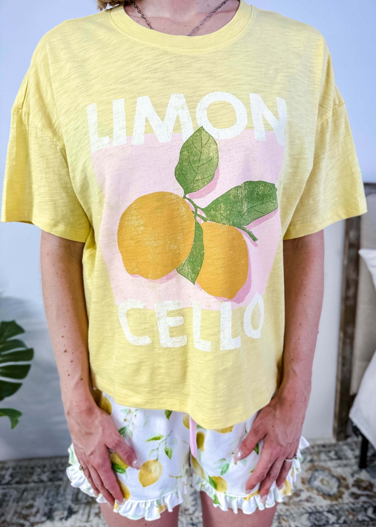 PJ SALVAGE — La Dolce Spritz Limoncello Graphic Tee & Lemon Zest Short Set shown on model in bedroom setting, close up shot of the Limoncello graphic print Tee shirt