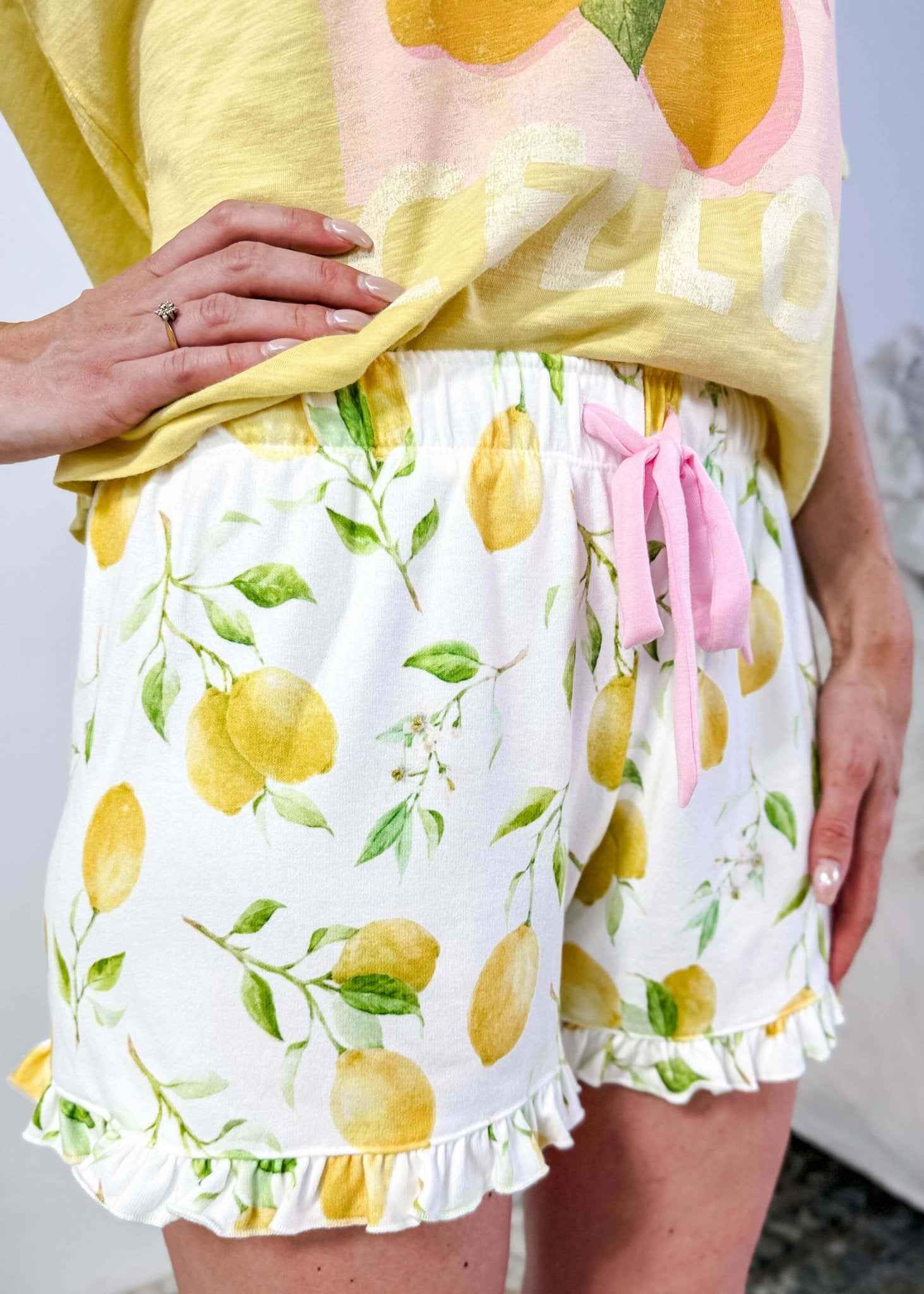 PJ SALVAGE — La Dolce Spritz Limoncello Graphic Tee & Lemon Zest Short Set shown on model in bedroom setting, close up shot of short print and details