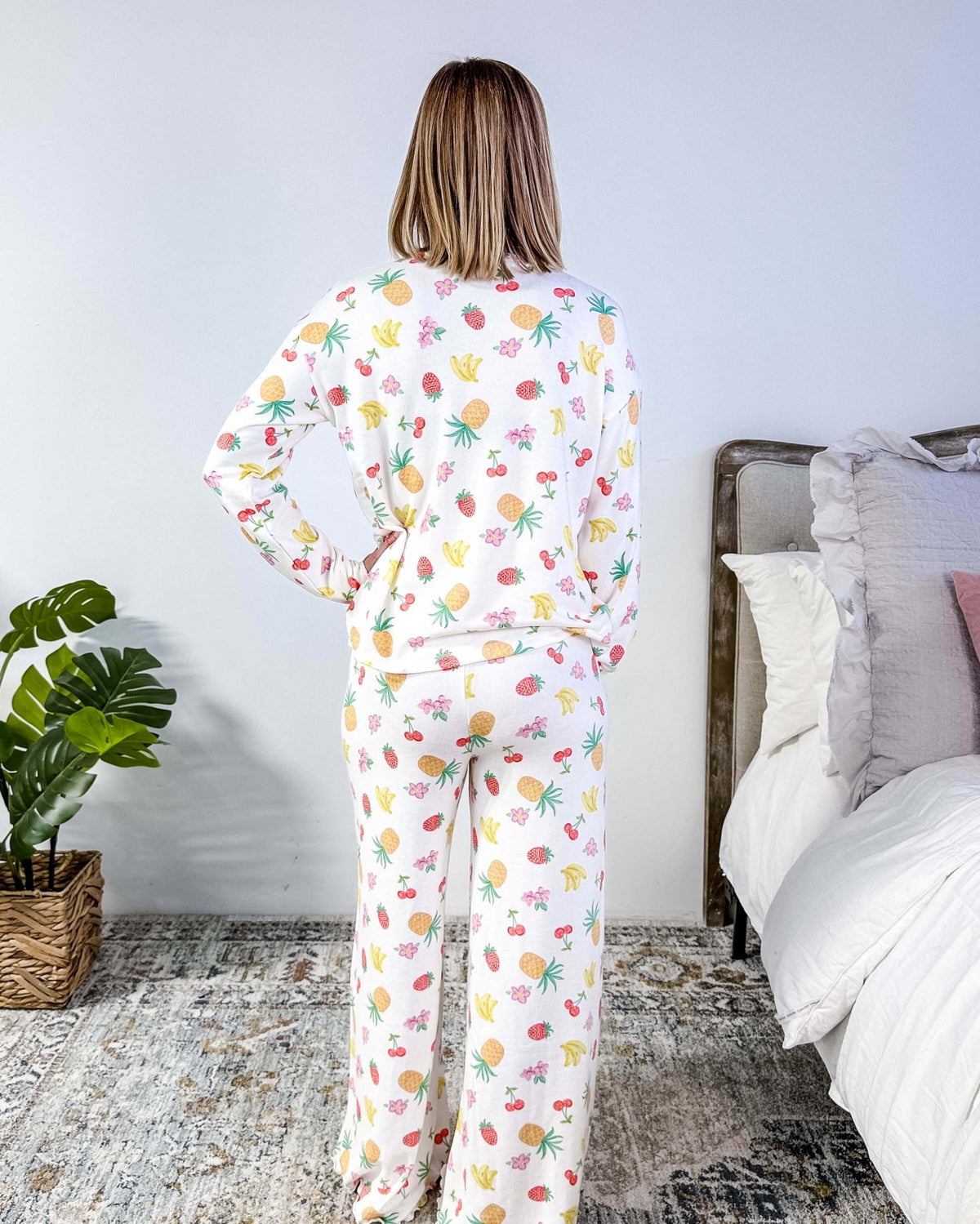 PJ SALVAGE — Viva la Vida Fruit Fiesta Long Sleeve & Pant Set worn on model in a bedroom setting, showing full length of the fruit print pj set from the back profile