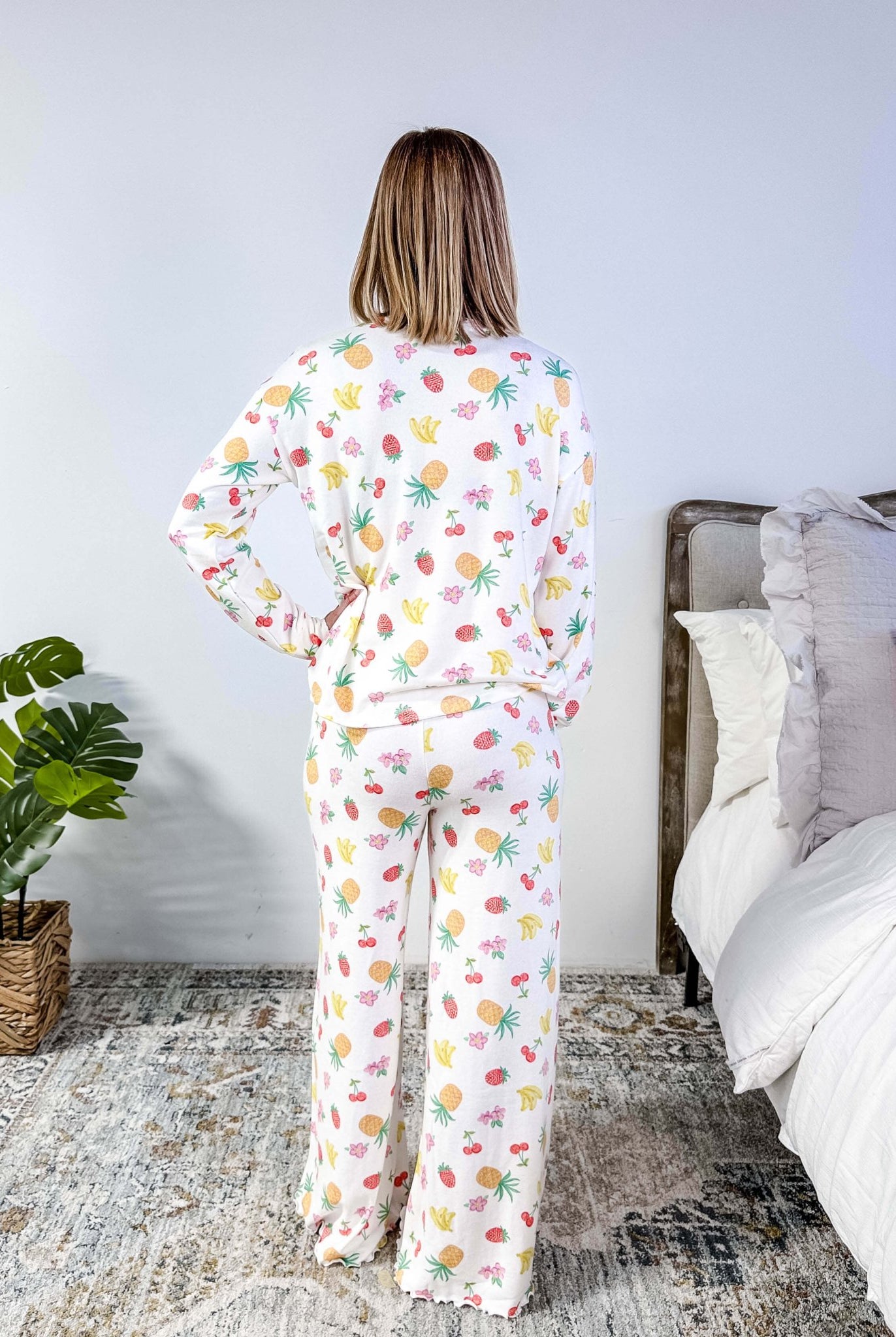 PJ SALVAGE — Viva la Vida Fruit Fiesta Long Sleeve & Pant Set worn on model in a bedroom setting, showing full length of the fruit print pj set from the back profile