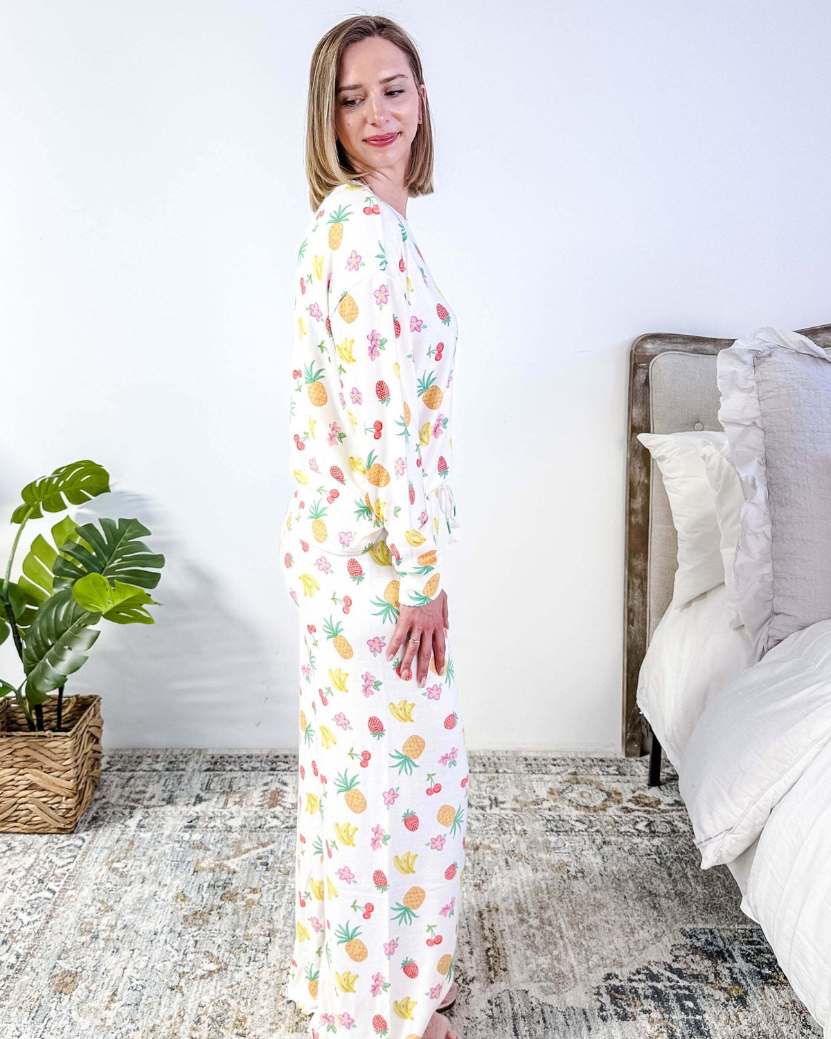 PJ SALVAGE — Viva la Vida Fruit Fiesta Long Sleeve & Pant Set worn on model in a bedroom setting, showing full length of the fruit print pj set from a side profile