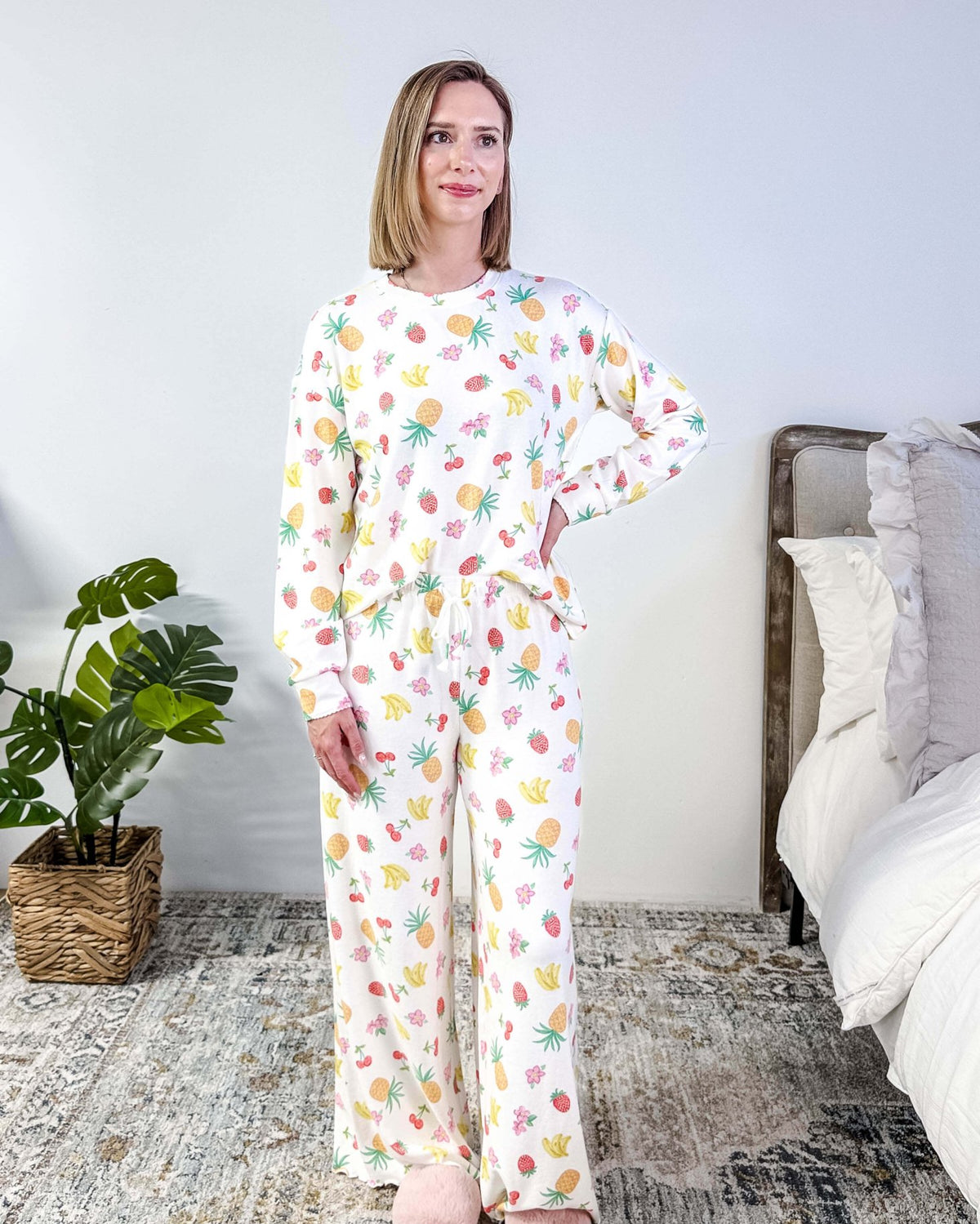 PJ SALVAGE — Viva la Vida Fruit Fiesta Long Sleeve & Pant Set worn on model in a bedroom setting, showing full length of the fruit print pj set with the top tucked in to show the drawstring