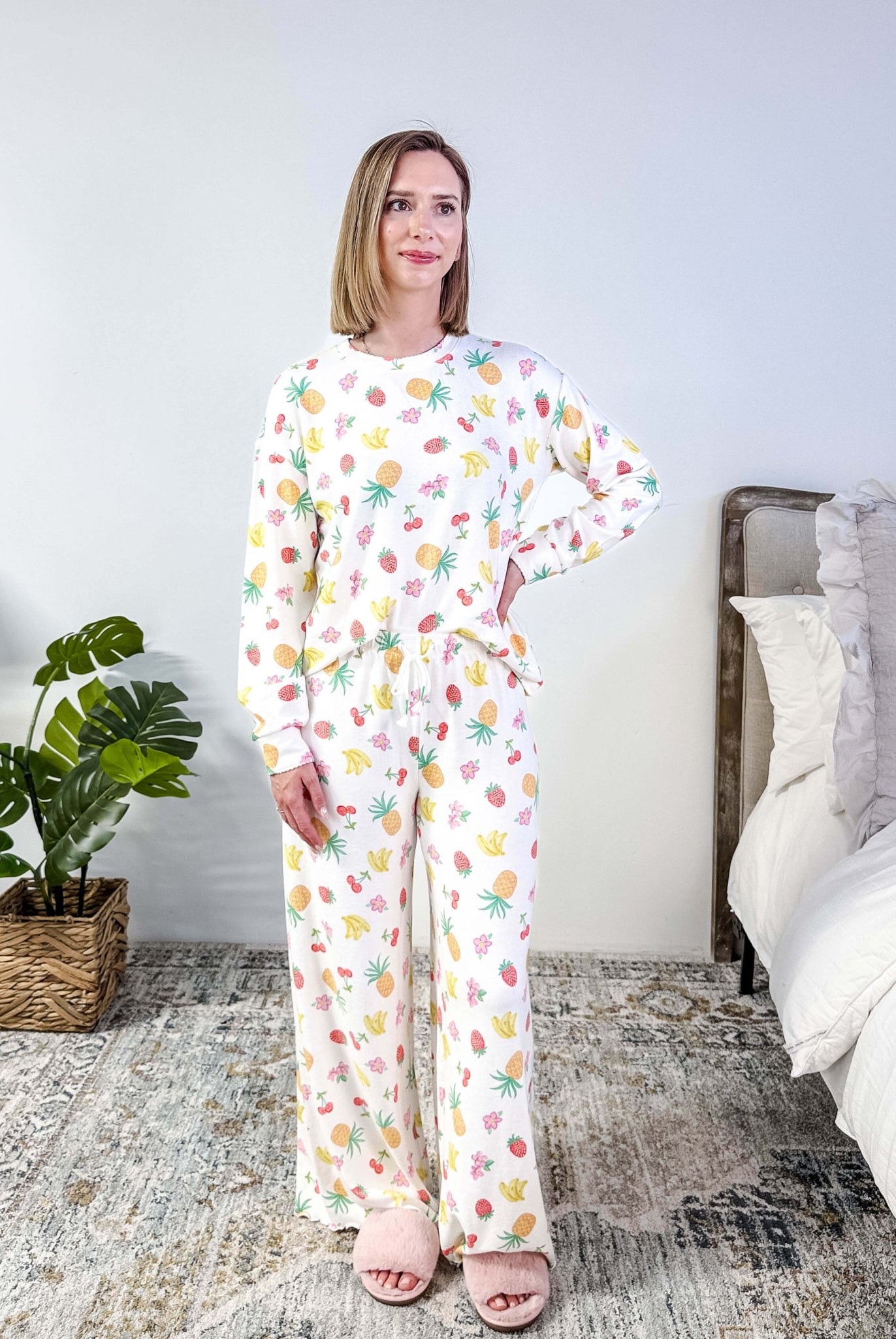 PJ SALVAGE — Viva la Vida Fruit Fiesta Long Sleeve & Pant Set worn on model in a bedroom setting, showing full length of the fruit print pj set with the top tucked in to show the drawstring
