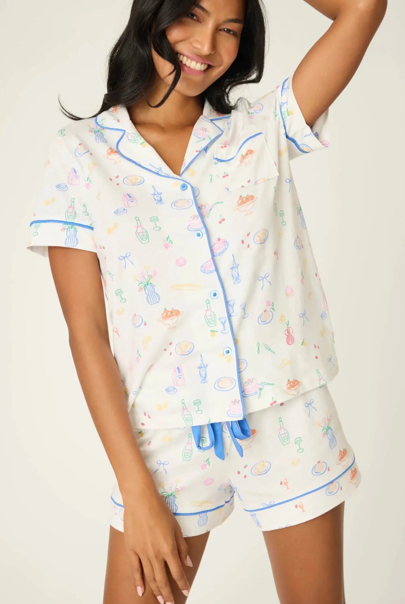 PJ Salvage Whimsy Button Up & Short Short Set in playful print with blue accents modeled by a smiling woman.