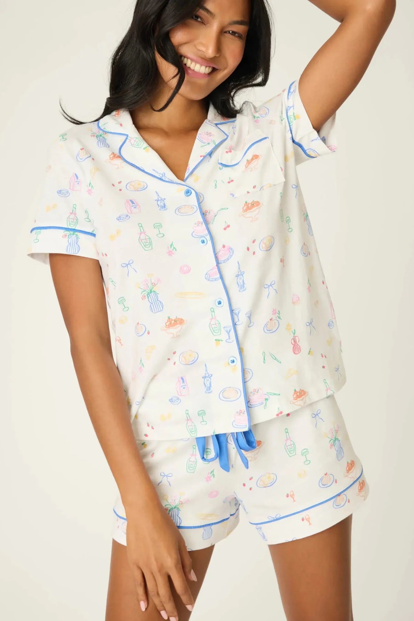 PJ Salvage Whimsy Button Up & Short Short Set in playful print with blue accents modeled by a smiling woman.