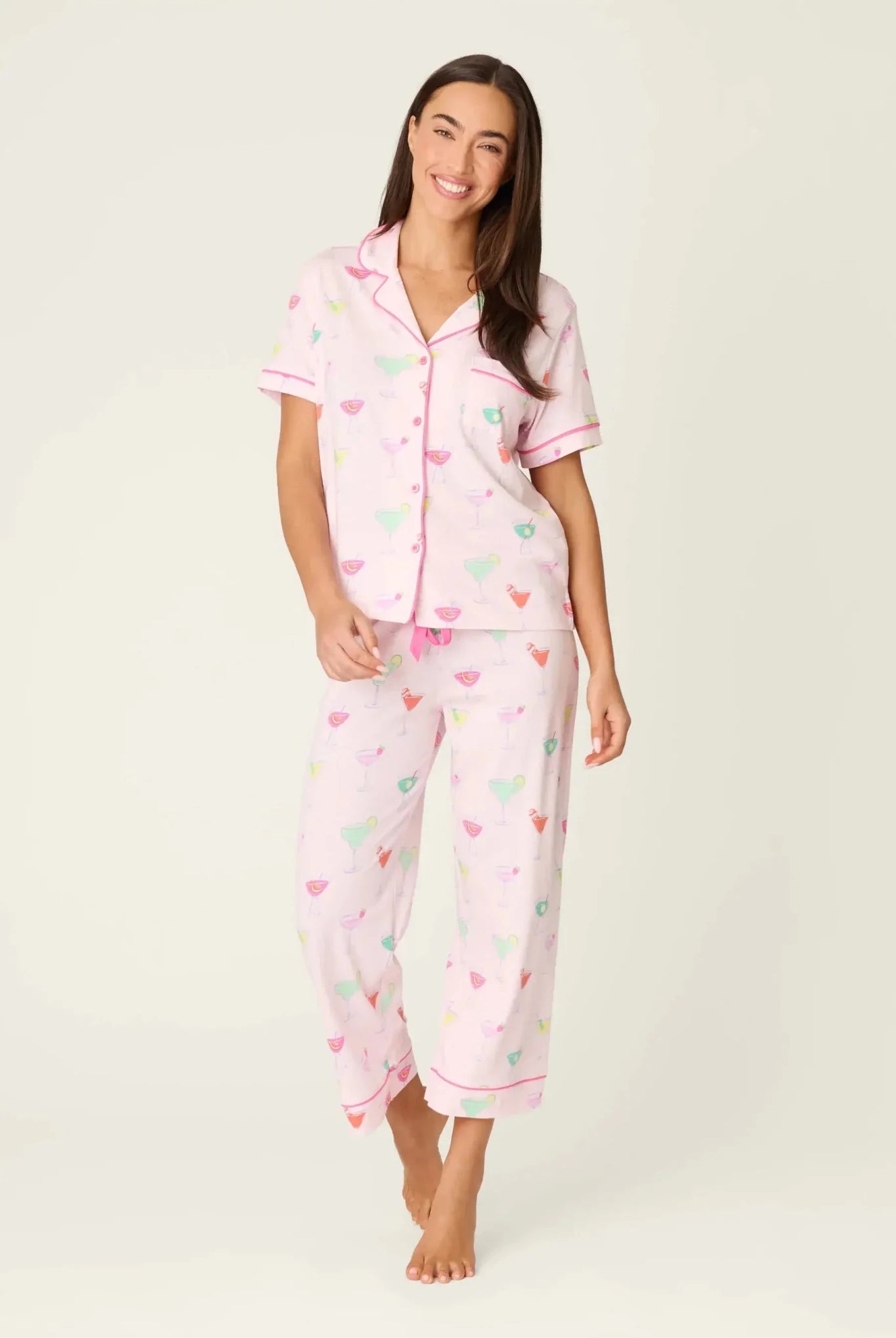 PJ SALVAGE Whimsy Cropped PJ Set in Light Pink Sip Happens print showing cocktail glasses in various colours. Model stands wearing the set against a light background showing the full length