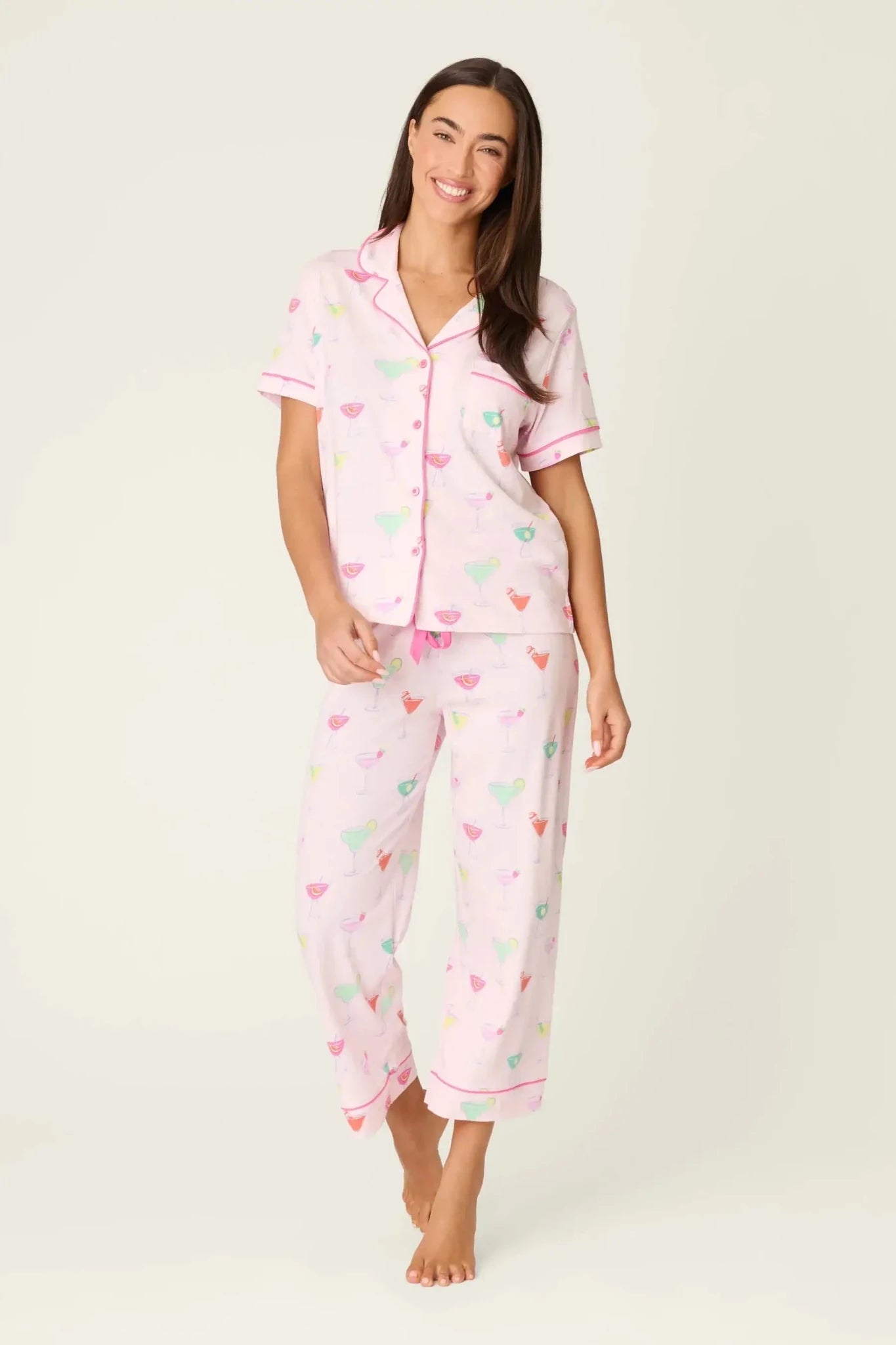PJ SALVAGE Whimsy Cropped PJ Set in Light Pink Sip Happens print showing cocktail glasses in various colours. Model stands wearing the set against a light background showing the full length