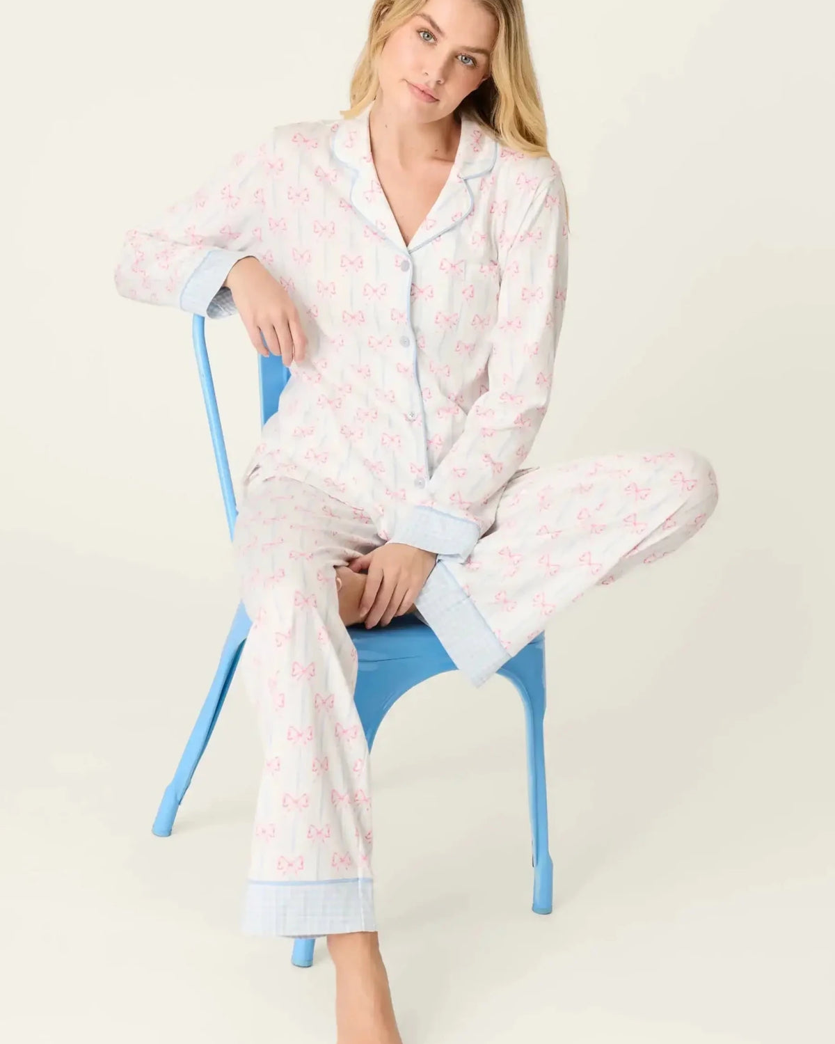 Model wearing Playful Prints Cotton-Modal Long Sleeve Pajama Set by PJ Salvage sitting on a blue chair.