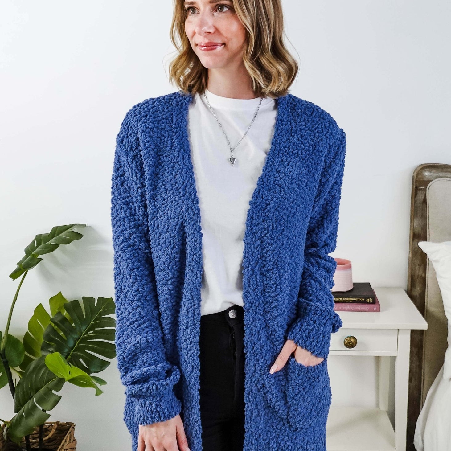 Popcorn Texture Open Summer Cardigan in blue, shown on model in a bedroom setting with hand in pocket
