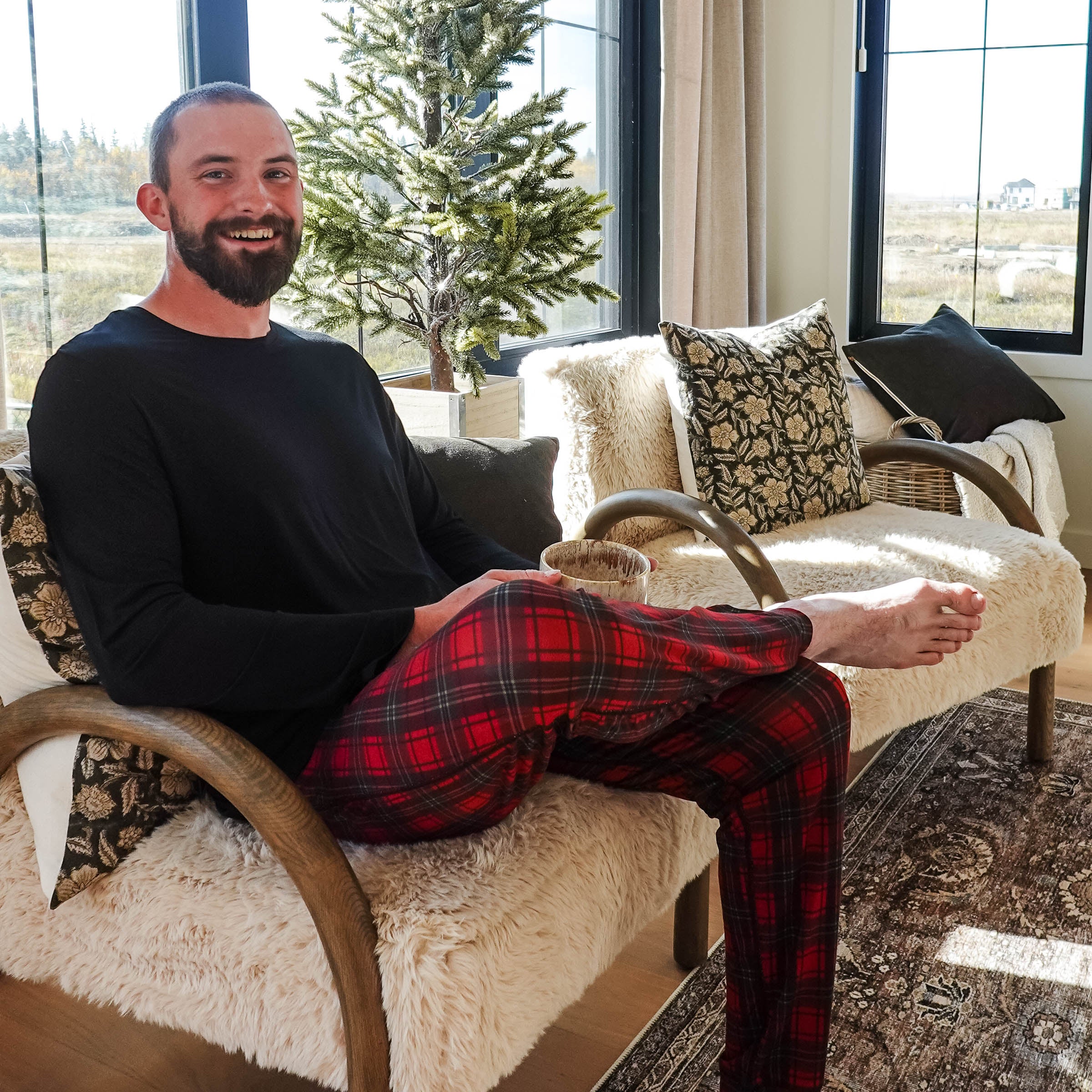 Man sitting on a cozy chair wearing Red Plaid Unisex Bamboo Jogger by Bob's Sleepwear Co.