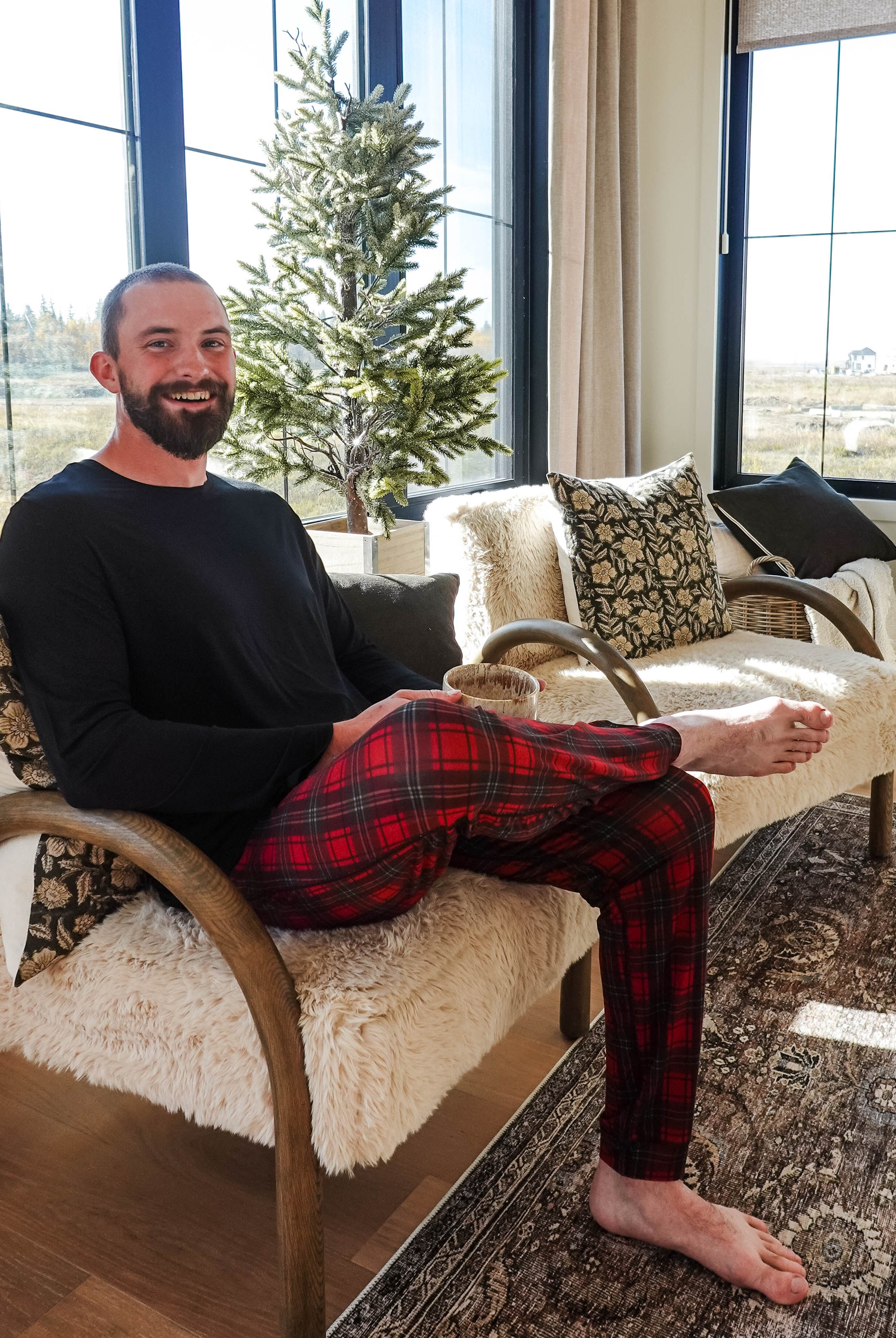 Man sitting on a cozy chair wearing Red Plaid Unisex Bamboo Jogger by Bob's Sleepwear Co.