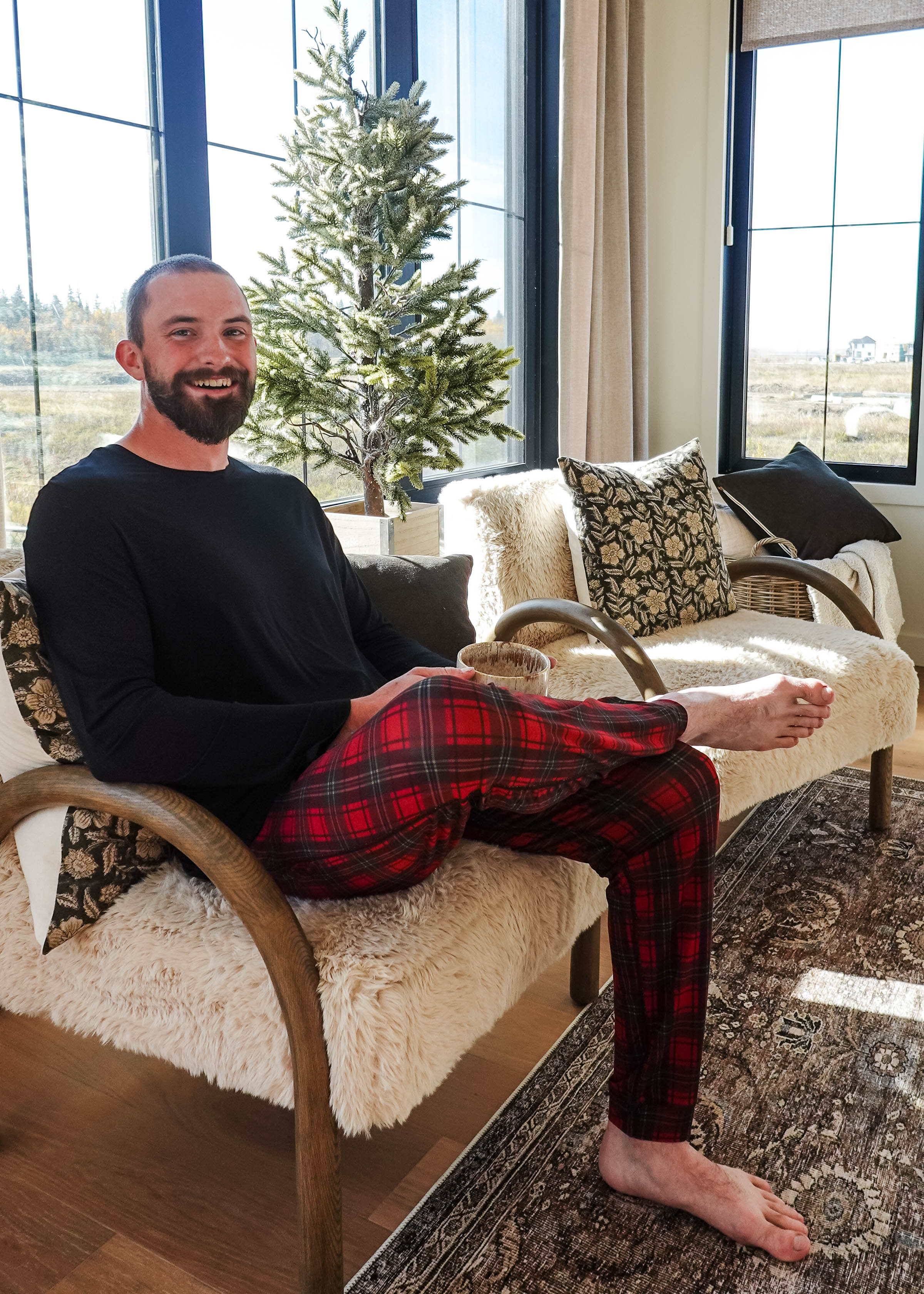 Man sitting on a cozy chair wearing Red Plaid Unisex Bamboo Jogger by Bob's Sleepwear Co.
