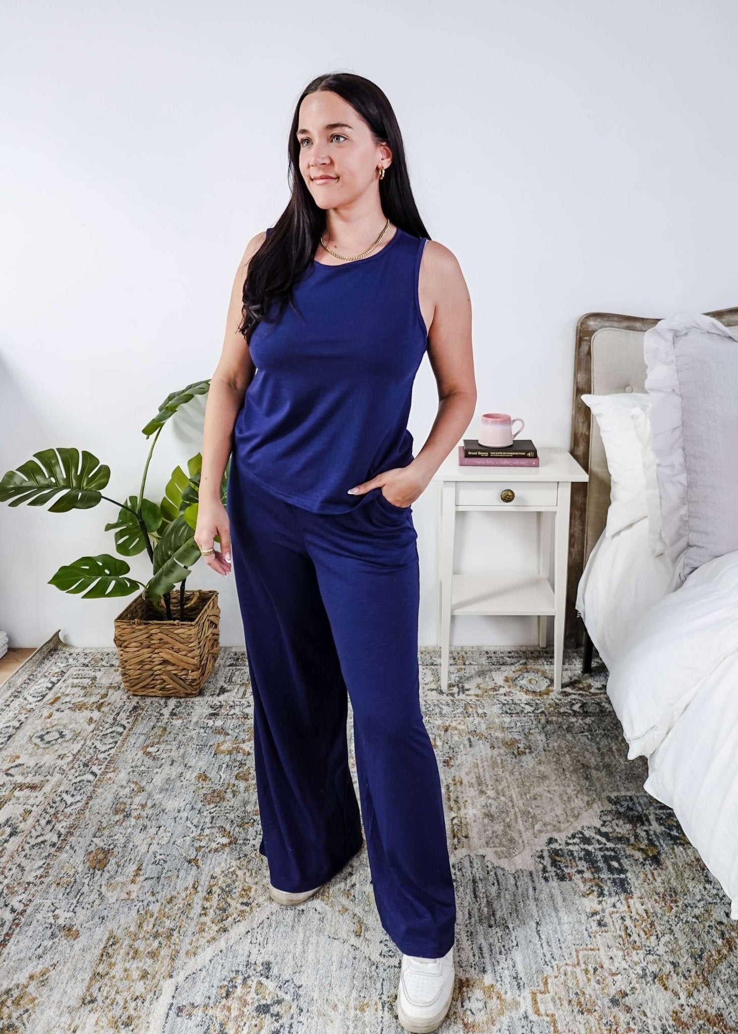 Woman wearing a sleepwear set with a navy sleeveless top and pants in a home setting.