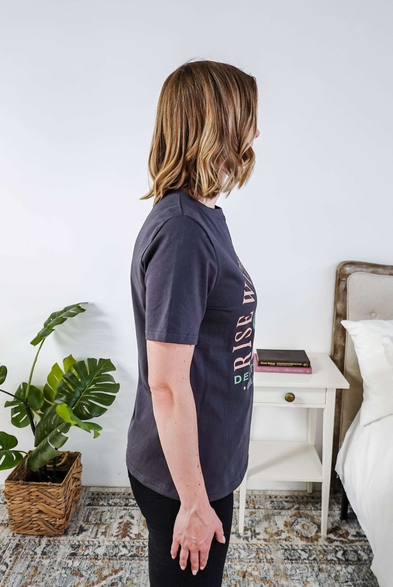 women wearing a dark grey graphic t-shirt with the saying rise with the sun death valley california