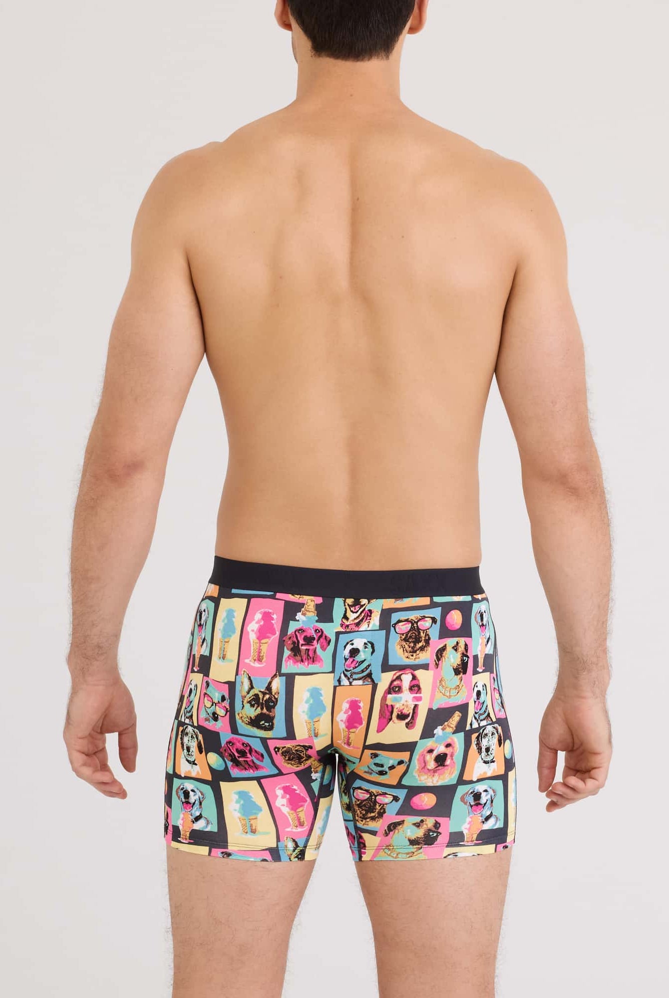 Back view of a man wearing Vibe Xtra Soft Comfort Boxer Brief featuring colorful dog prints.