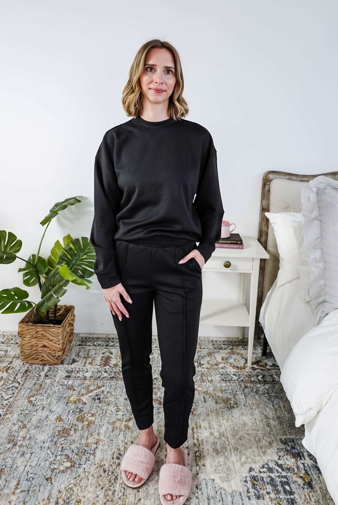 Woman wearing a black lounge outfit in a bedroom setting