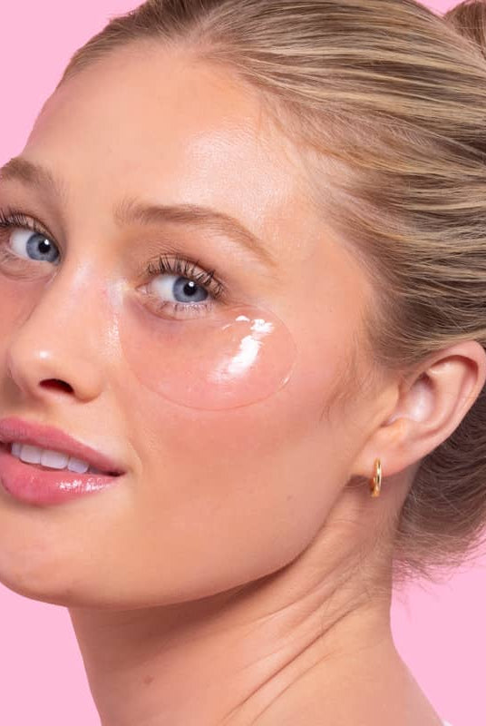 Woman with cosmetic patches under eyes on a pink background, Patchology Serve Chilled Rosé Eye Gels 5 pack antioxidant hydrating