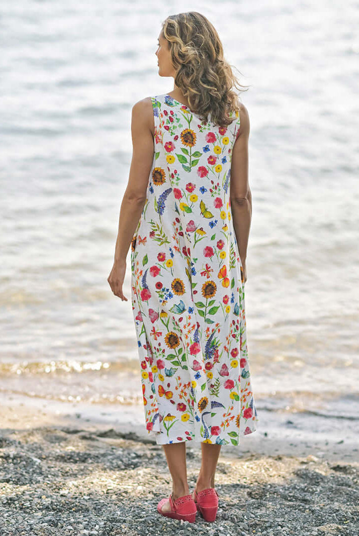 April Cornell Sister Garden Cotton Midi Floral Dress shown on a model against a beach background. Shot is of the back of the dress showing the length and fullness of the dress