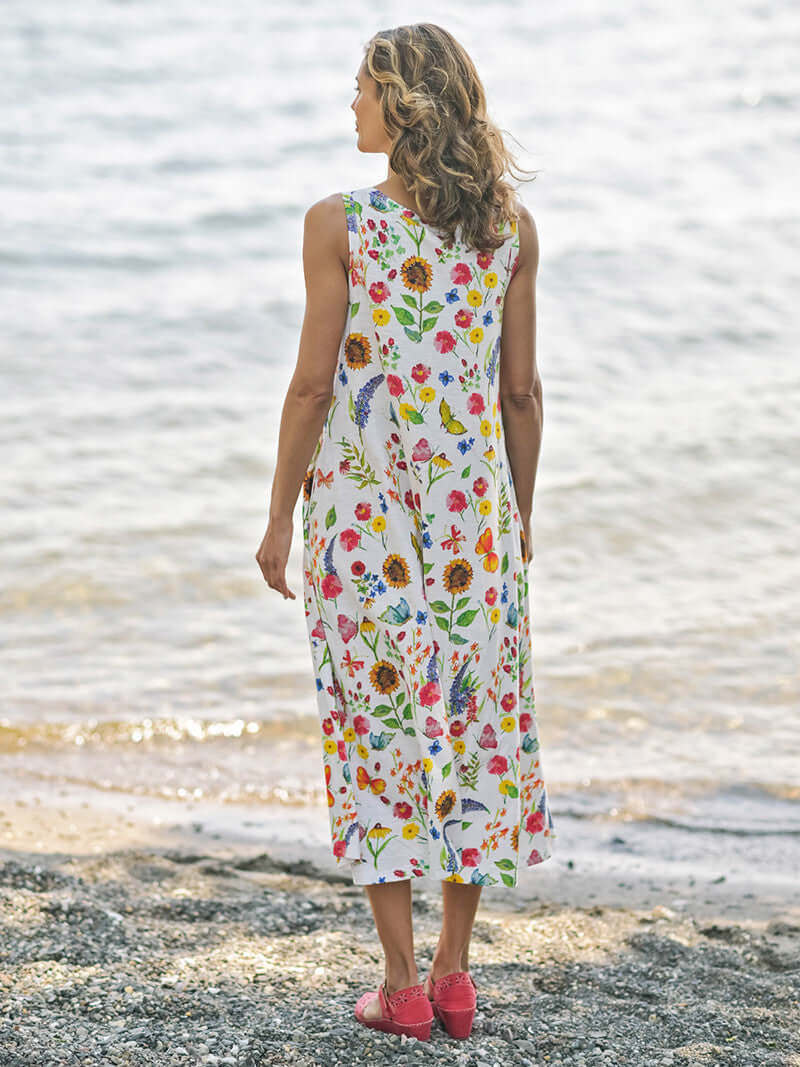 April Cornell Sister Garden Cotton Midi Floral Dress shown on a model against a beach background. Shot is of the back of the dress showing the length and fullness of the dress