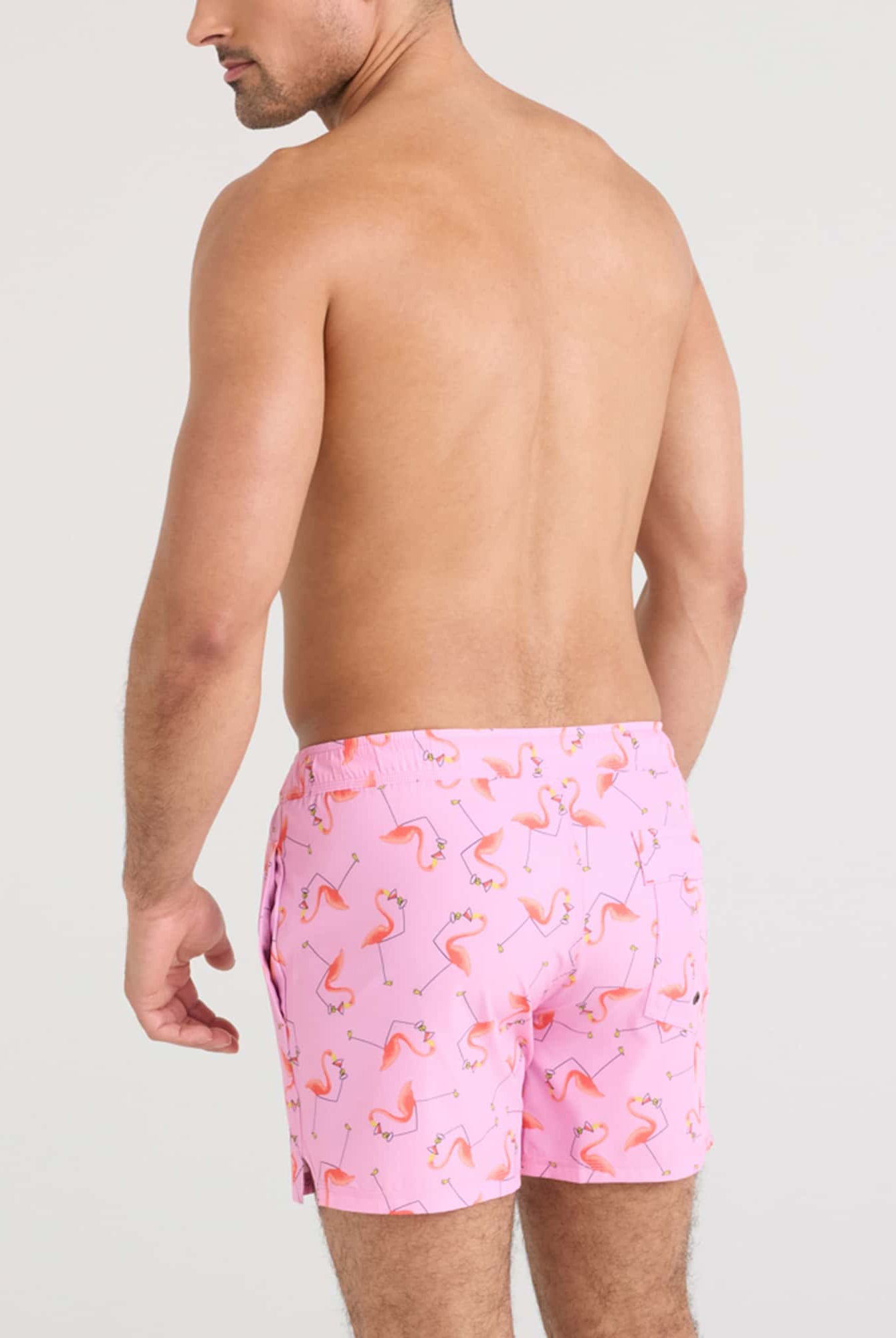 Man modeling the Oh Buoy 2N1 Volley Swim Short in pink flamingo pattern, showcasing a stylish summer look.
