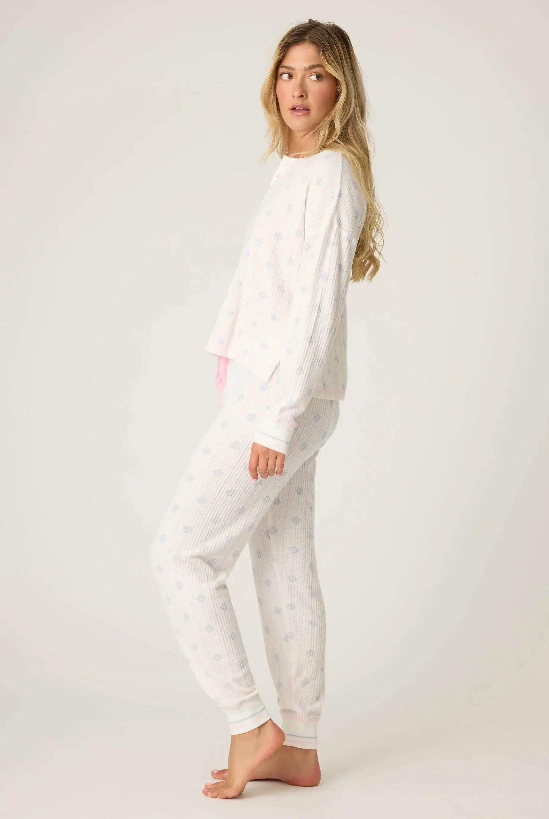 Woman wearing Snowflake Wishes Thermal PJ Set in ivory with snowflake pattern, featuring a cozy henley top and jogger pants.