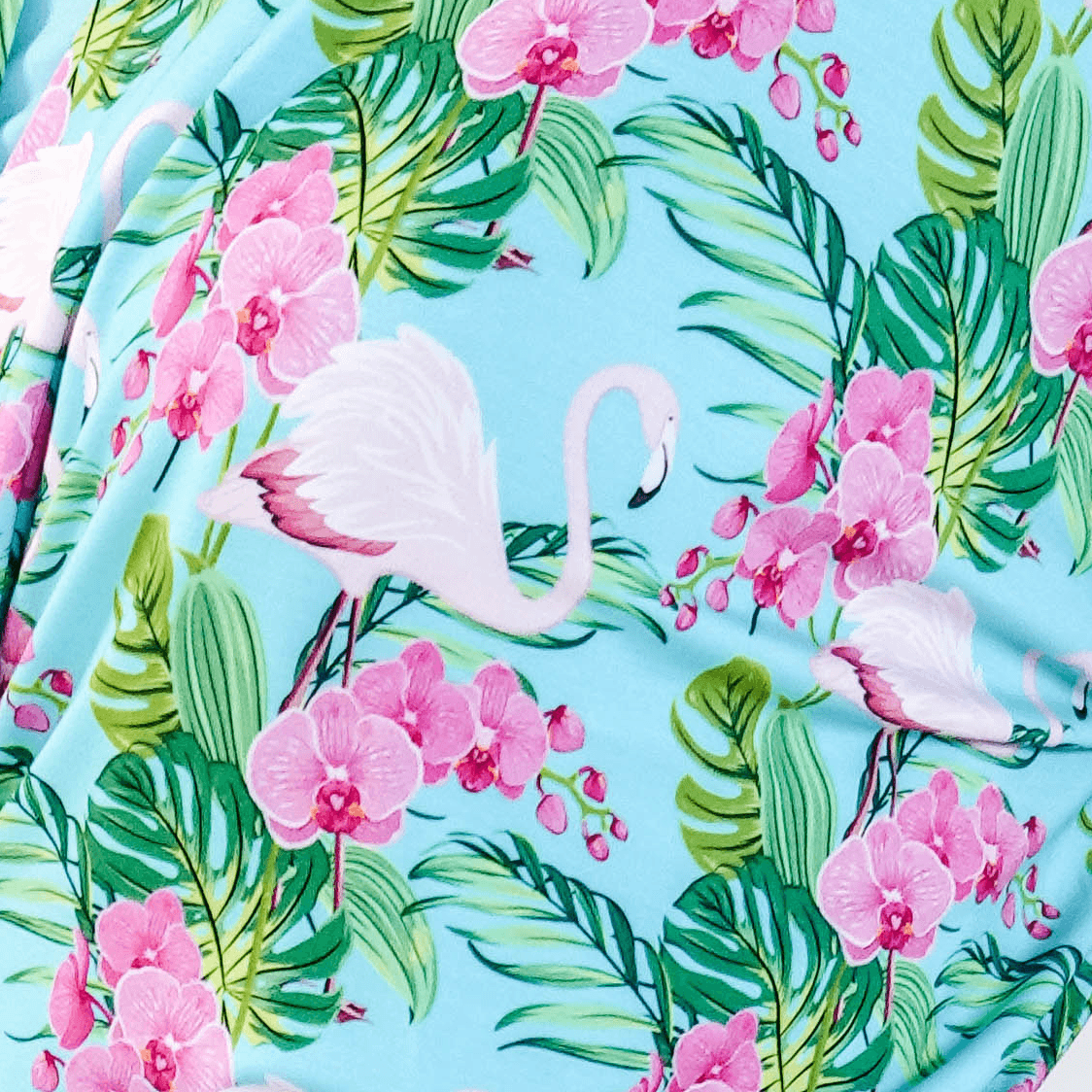 Tropic Like its Hot Print showing close up of fabric, texture and tropical flamingo and floral print on a light blue background