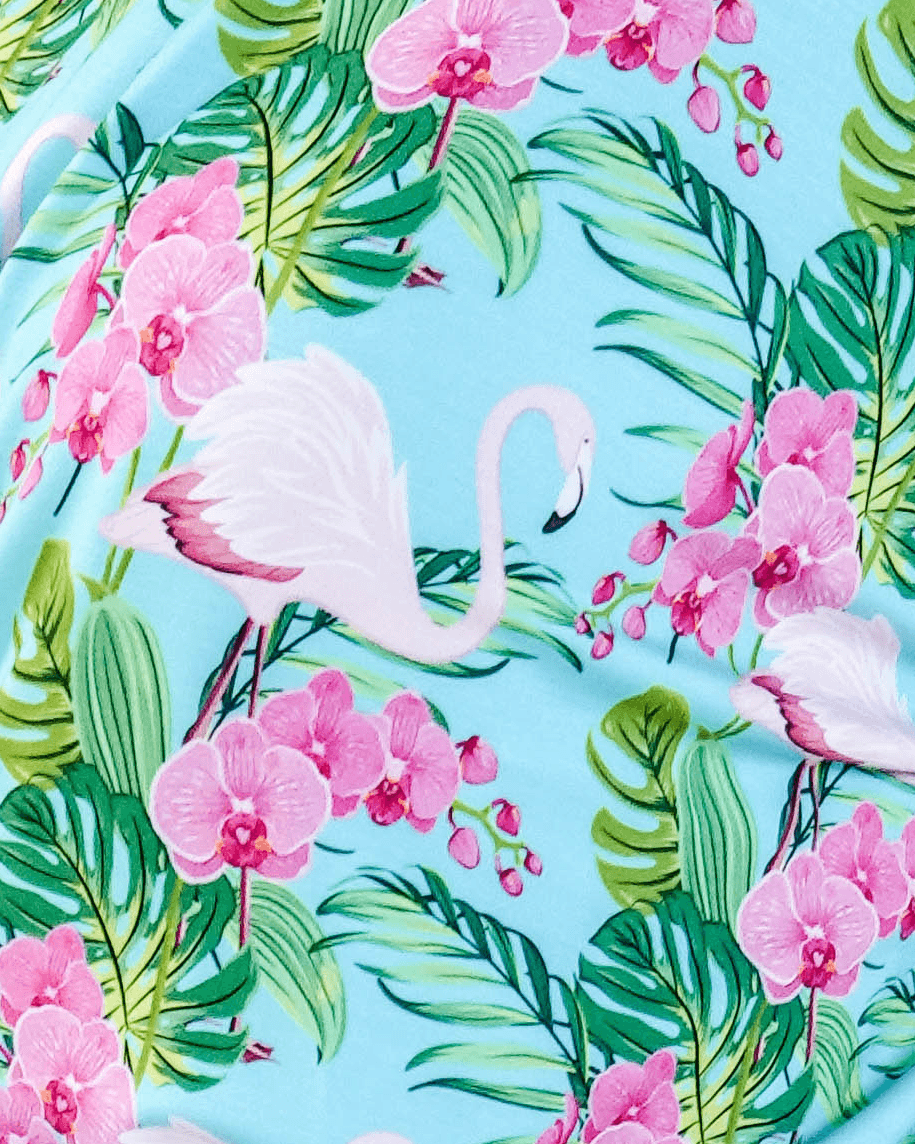 Tropic Like its Hot Print showing close up of fabric, texture and tropical flamingo and floral print on a light blue background