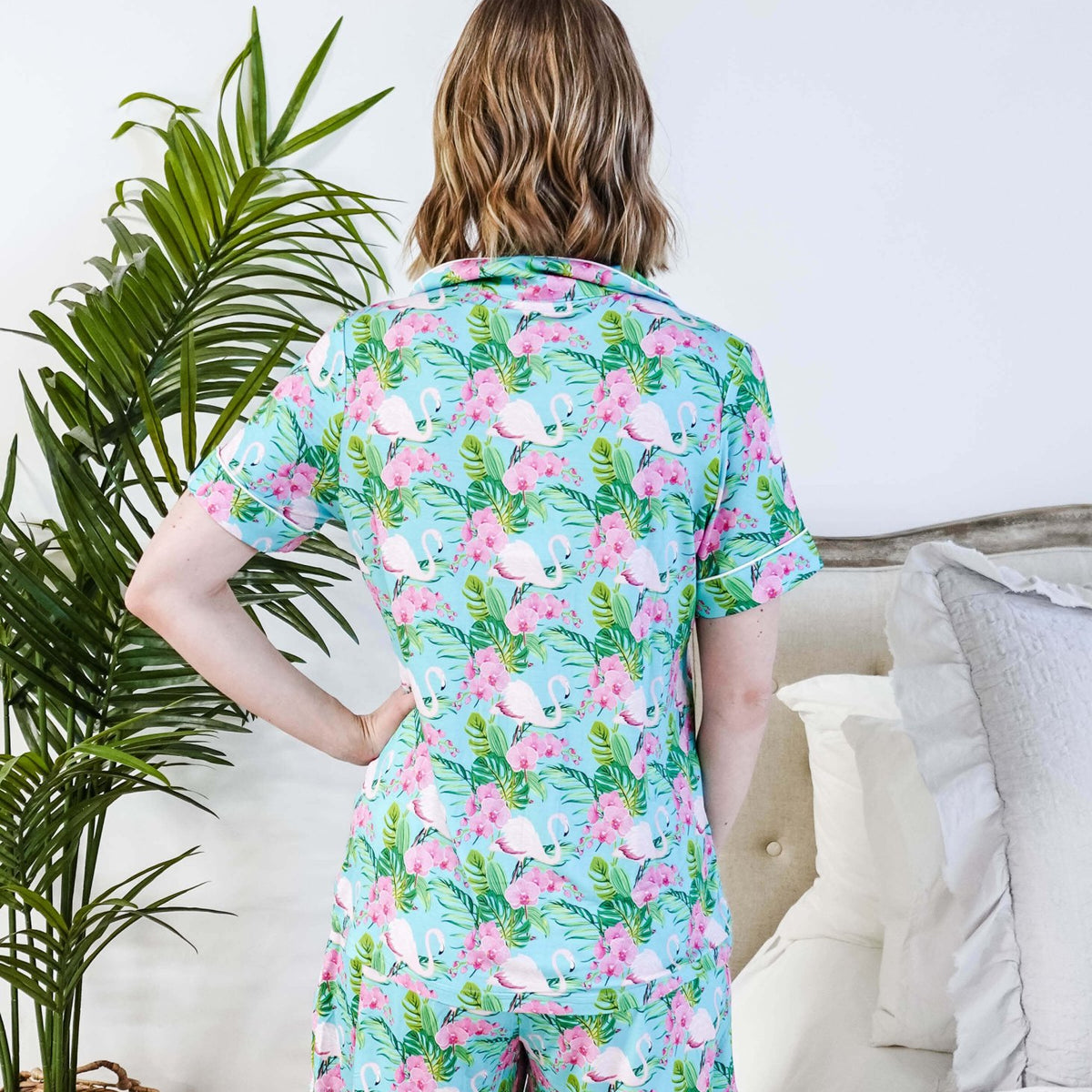 Back view of a woman wearing the Tropic Like It's Hot Bamboo Short Sleeve Pajama Set by Georgia Rylan, featuring a vibrant flamingo print.