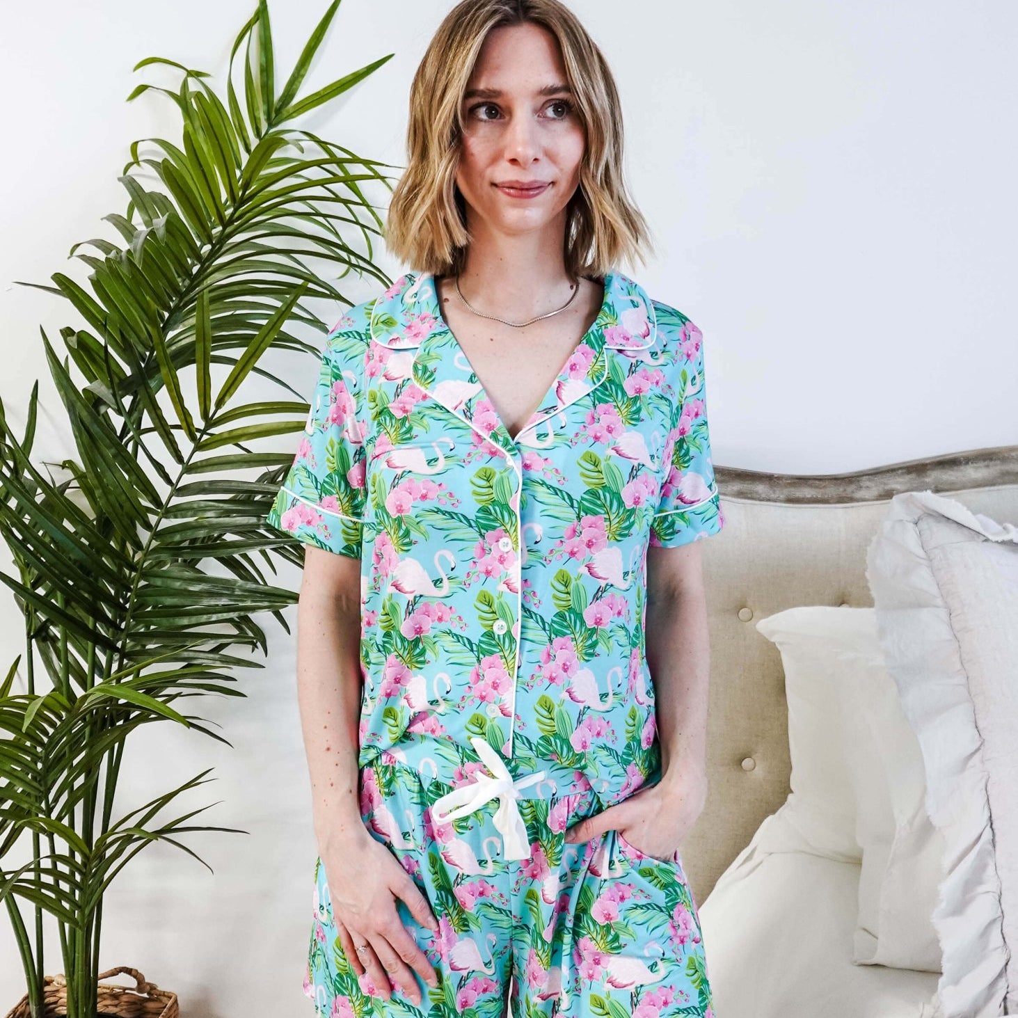 Model wearing Tropic Like It's Hot Bamboo Short Sleeve Pajama Set with pink flamingo and tropical orchid print.