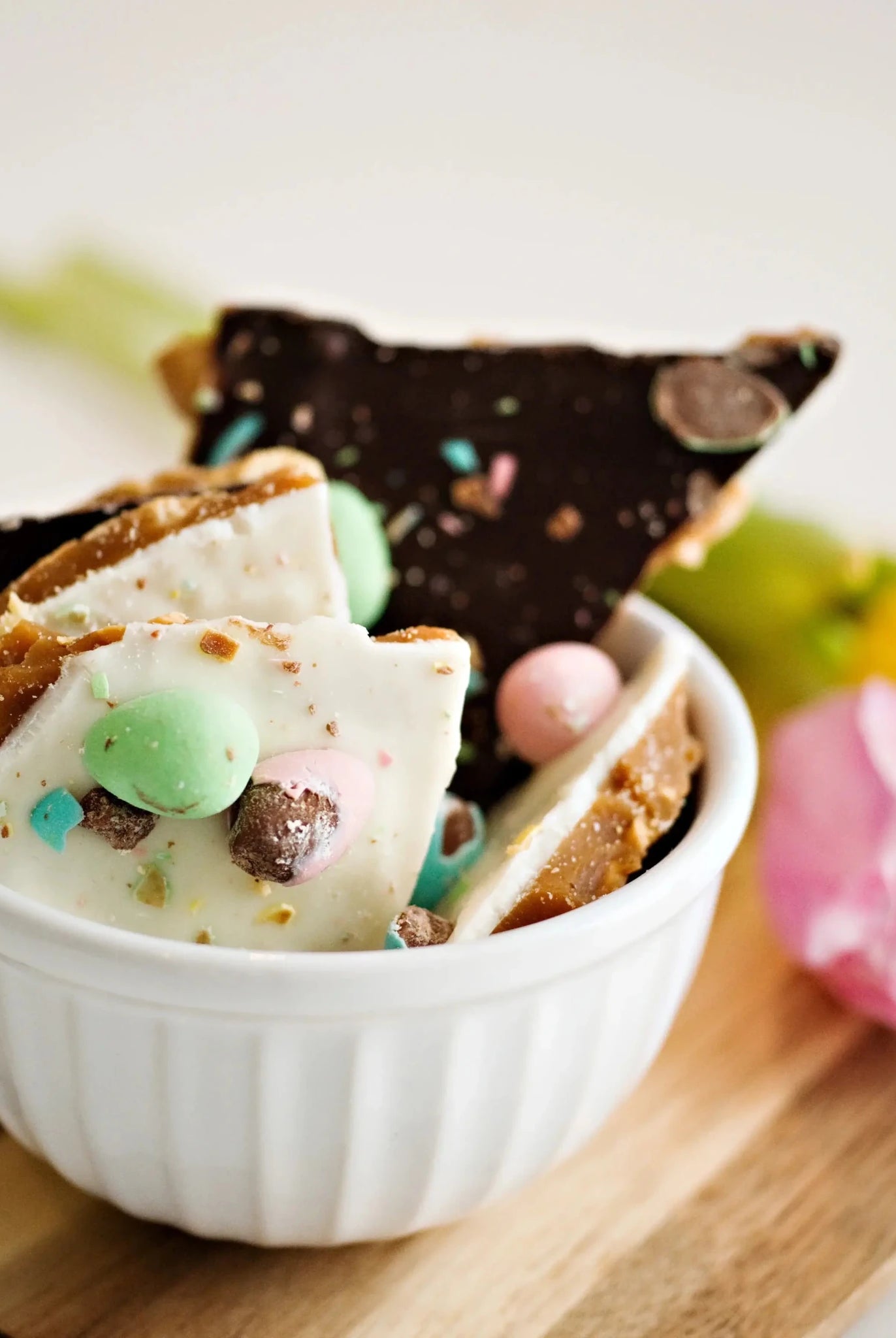 Utoffeea Canada Handcrafted Toffee pieces in a white bowl surrounded by flowers.